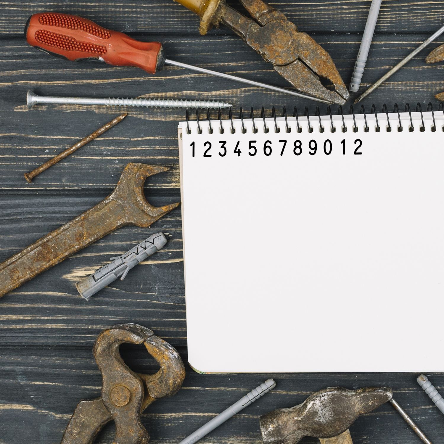 Assorted construction tools and measuring notebook with numbered page for DIY planning and home repair estimates, contractor work.