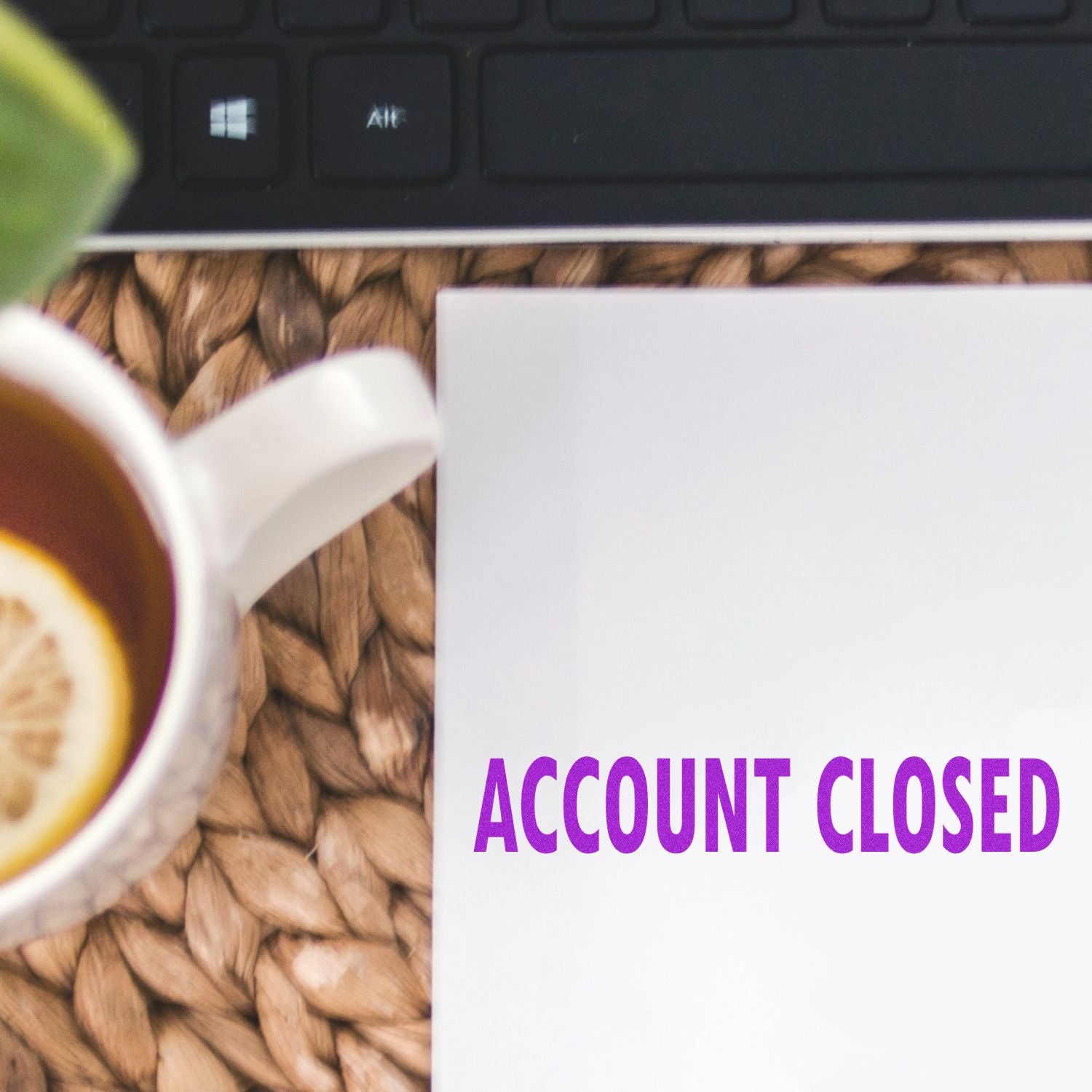 Coffee cup beside a keyboard and paper reading Account Closed on a desk background.