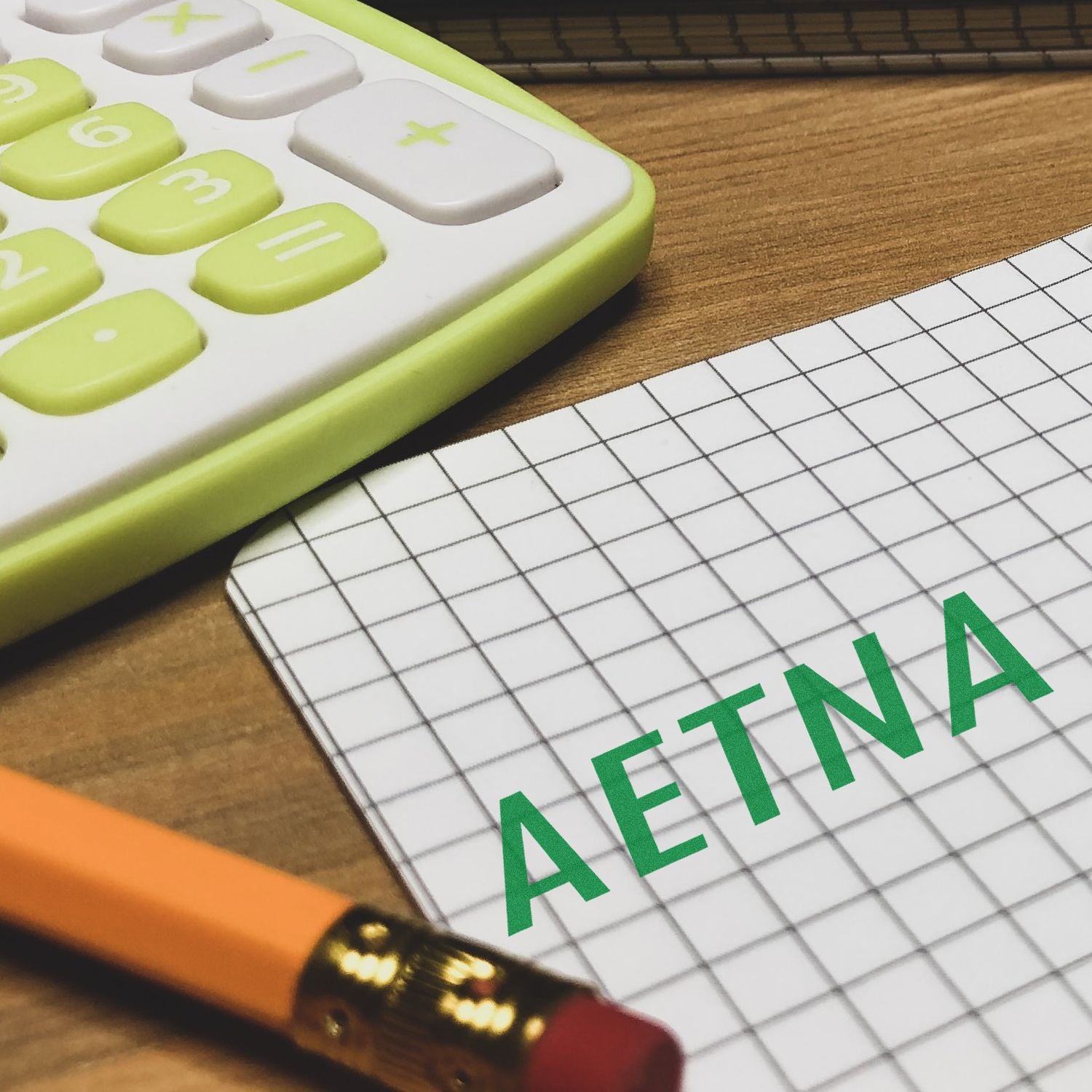 Aetna health insurance planning with calculator, graph paper, and pencil on desk