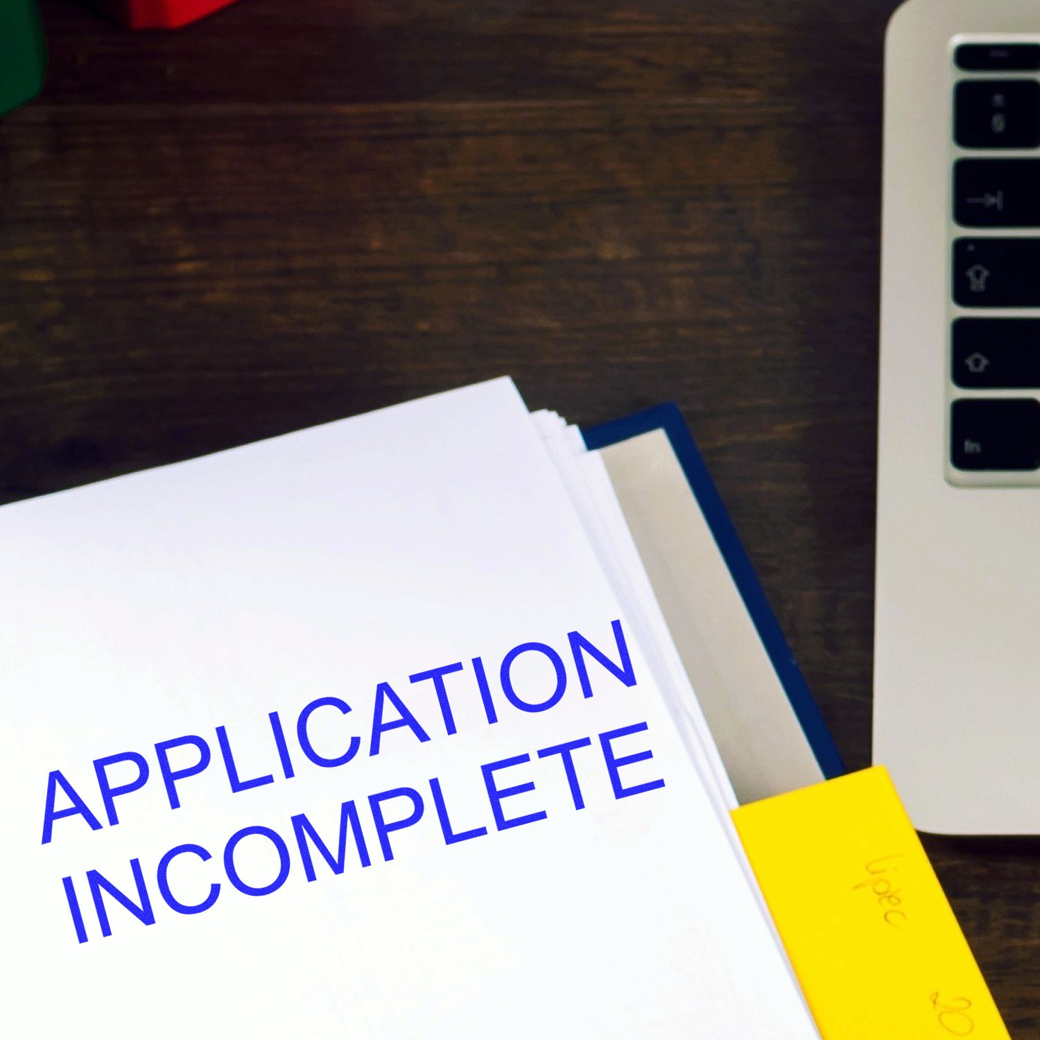 Application incomplete document on desk with sticky note, highlighting incomplete job application status for paperwork processing.
