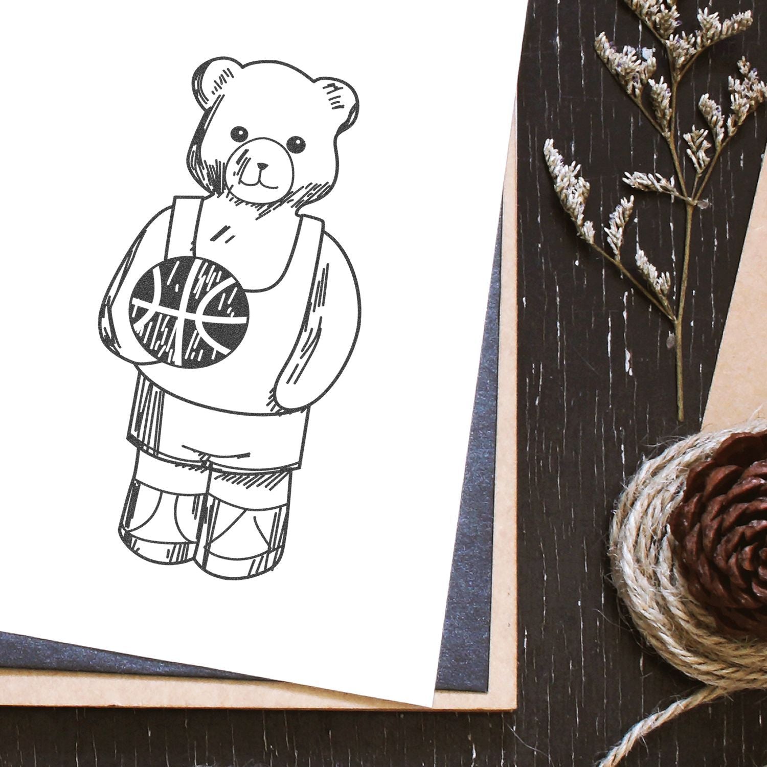 Cute teddy bear basketball drawing on paper with rustic craft decor and pinecone background