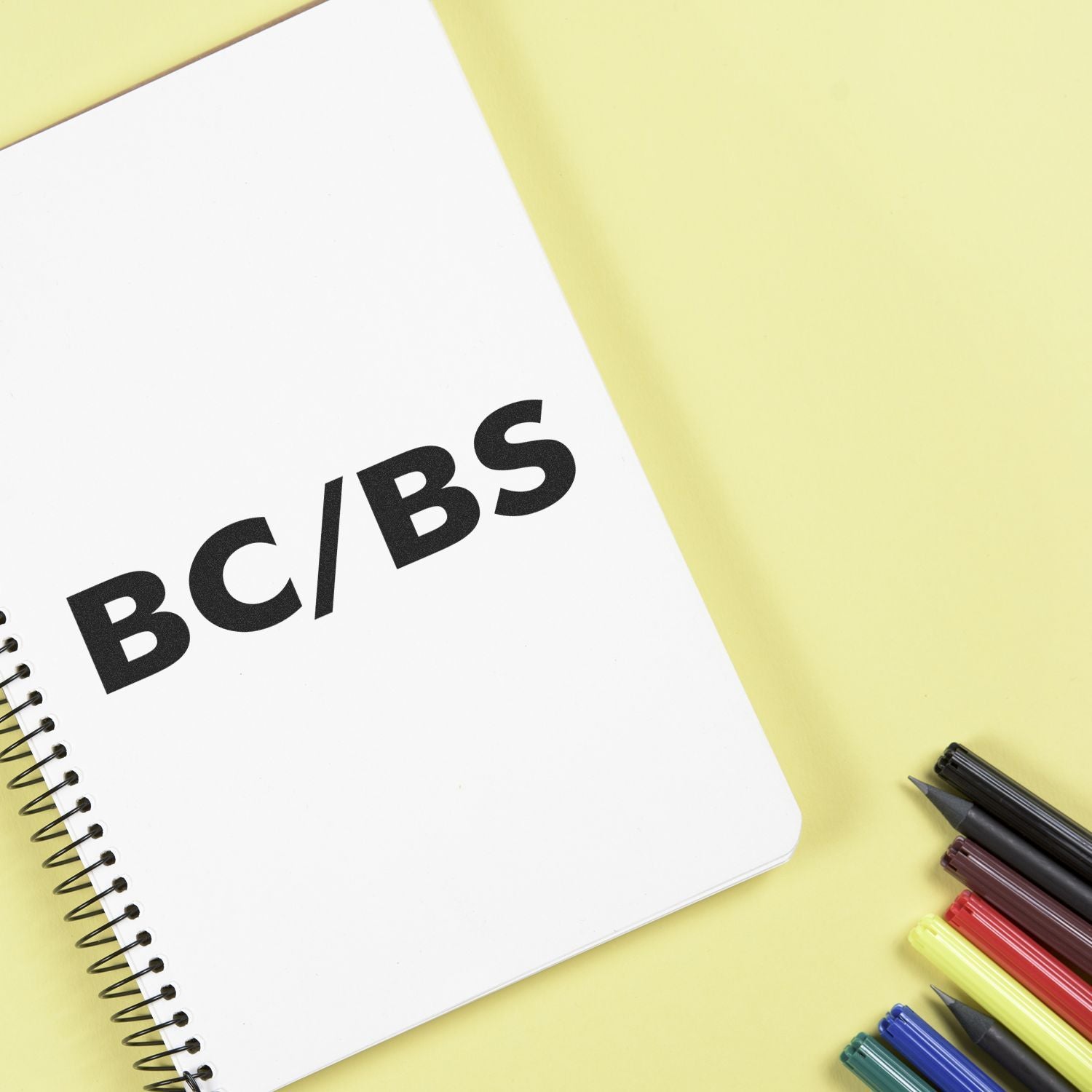 School notebook page with bold BCIBS text, with colored pens and markers for study and classroom learning.