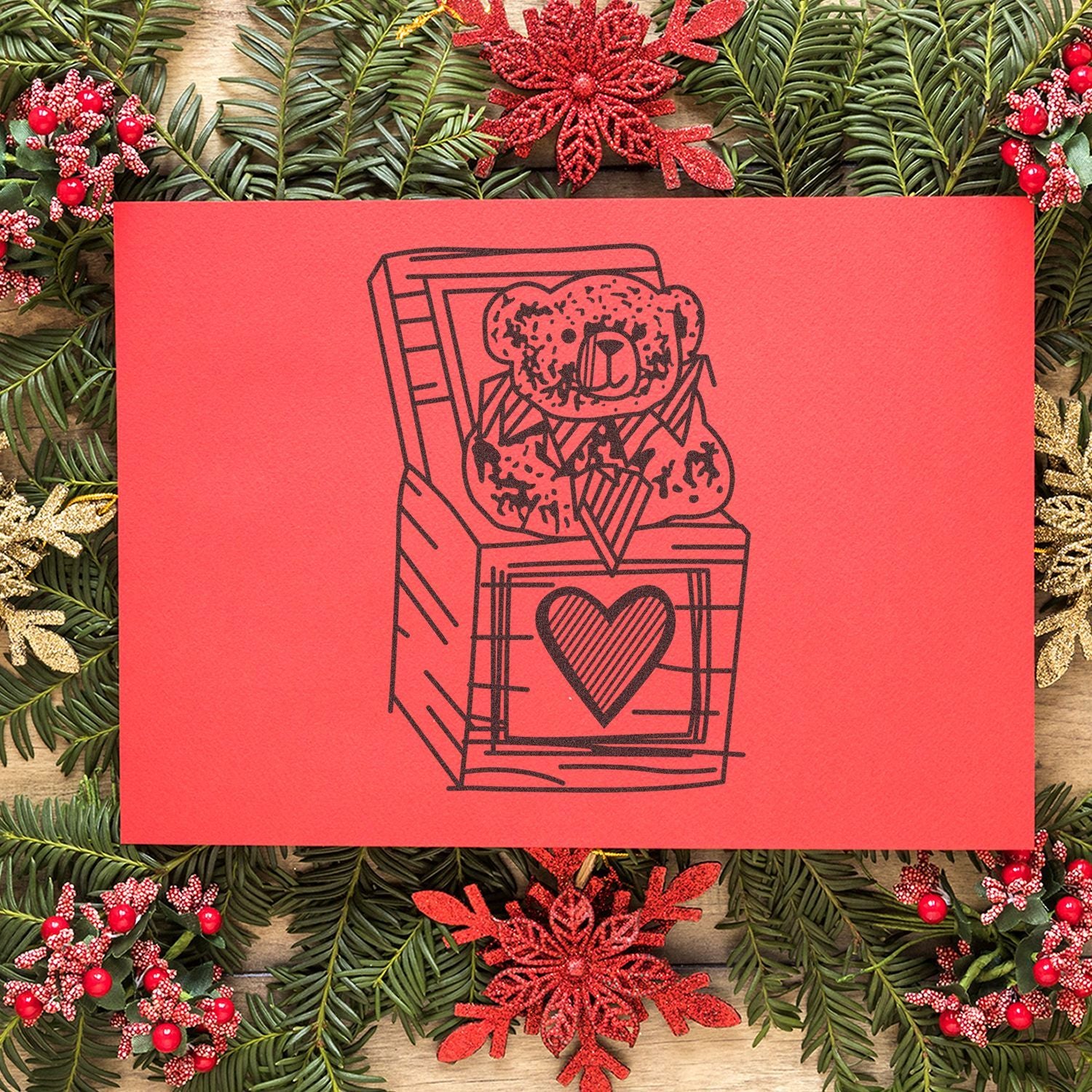 Red Valentines Day card with teddy bear graphic surrounded by festive pine branches and holiday decorations.