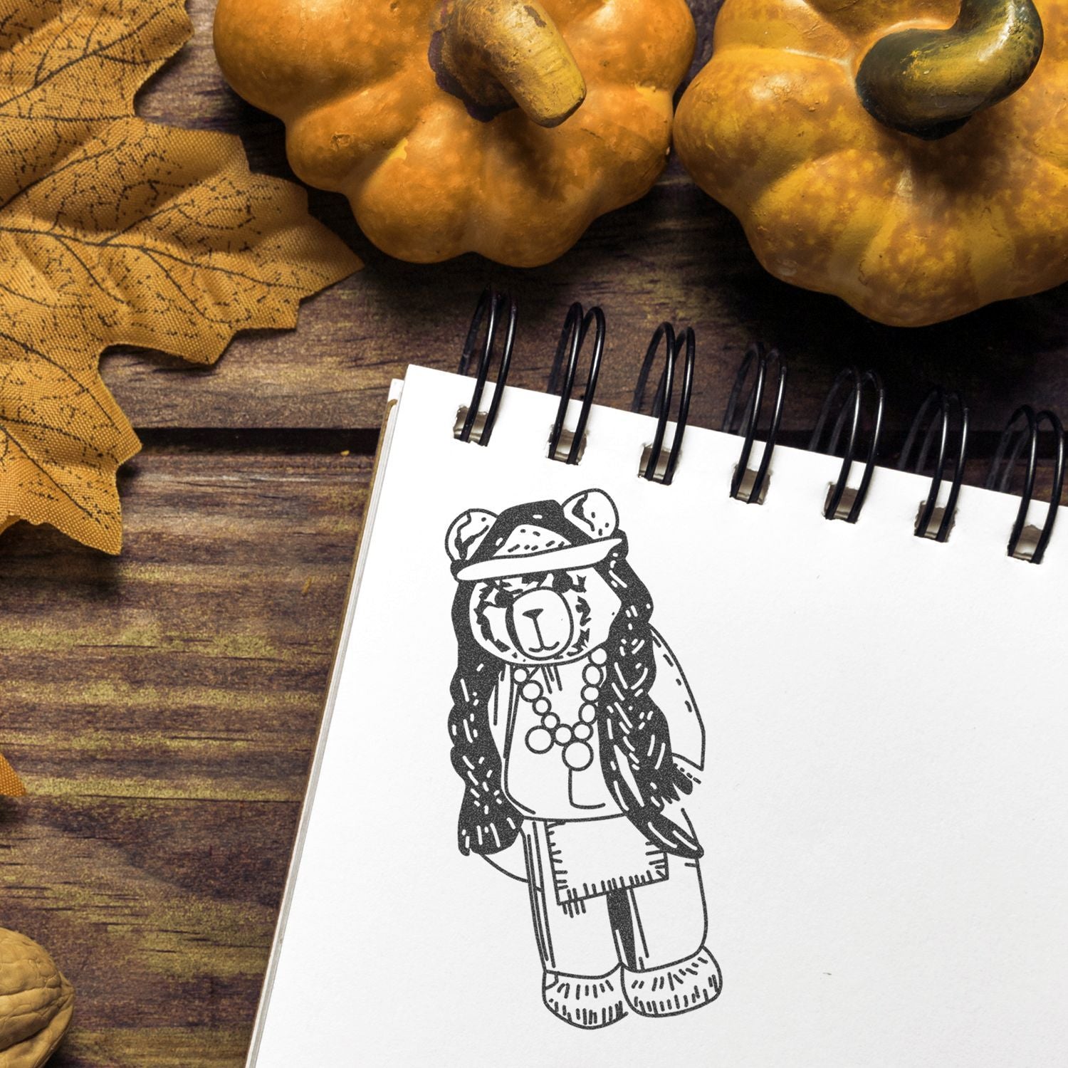 Autumn-themed notebook with bear illustration, pumpkins, and fall leaves on rustic wooden background