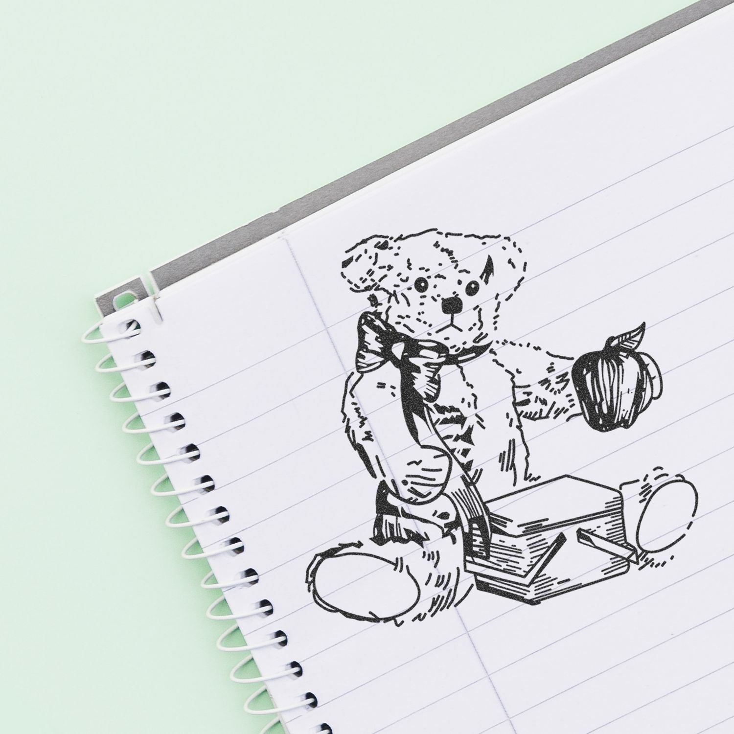 Spiral notebook with cute hand-drawn teddy bear illustration on lined paper against a mint green background