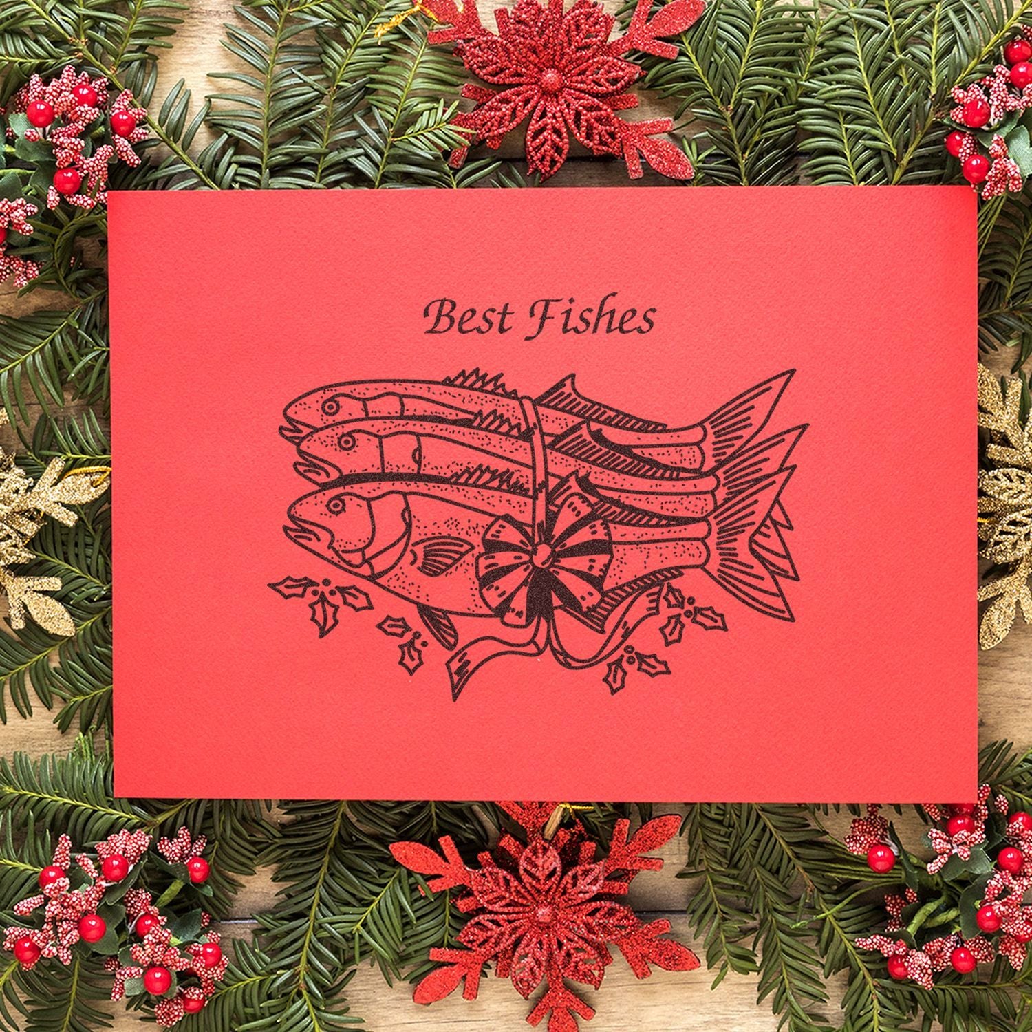 Red Best Fishes Christmas card with fish illustration, surrounded by evergreen wreath and festive holiday decorations.