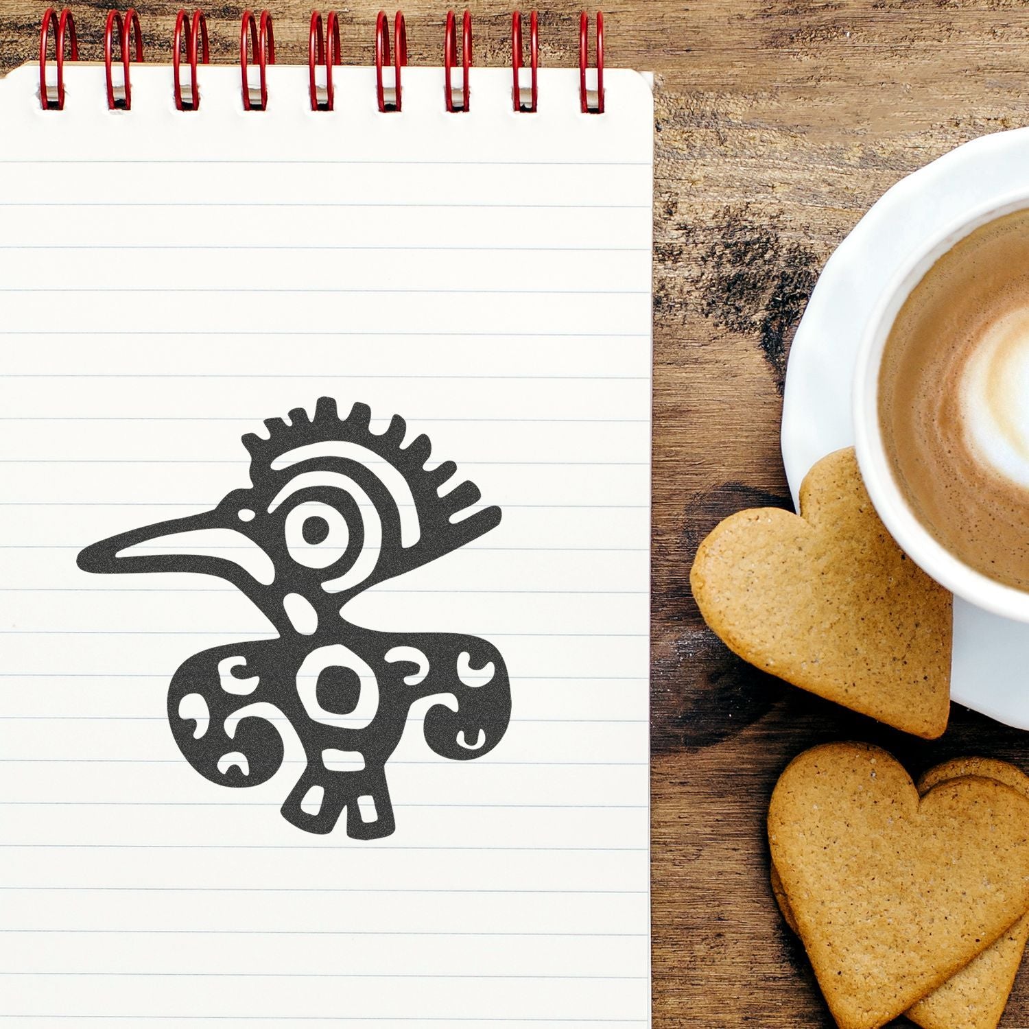 Blank spiral notebook with bird design beside coffee and heart-shaped cookies on a rustic wooden table.