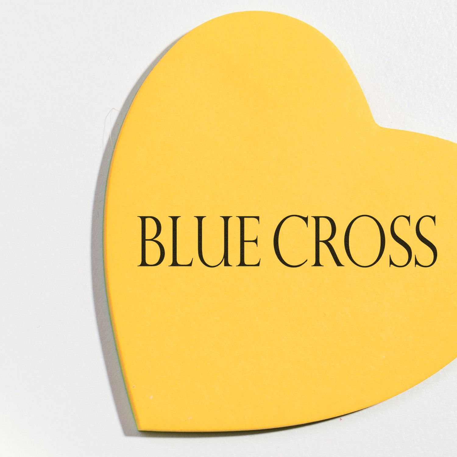 Close-up of the Blue Cross logo on a yellow card, used for branding and identification.