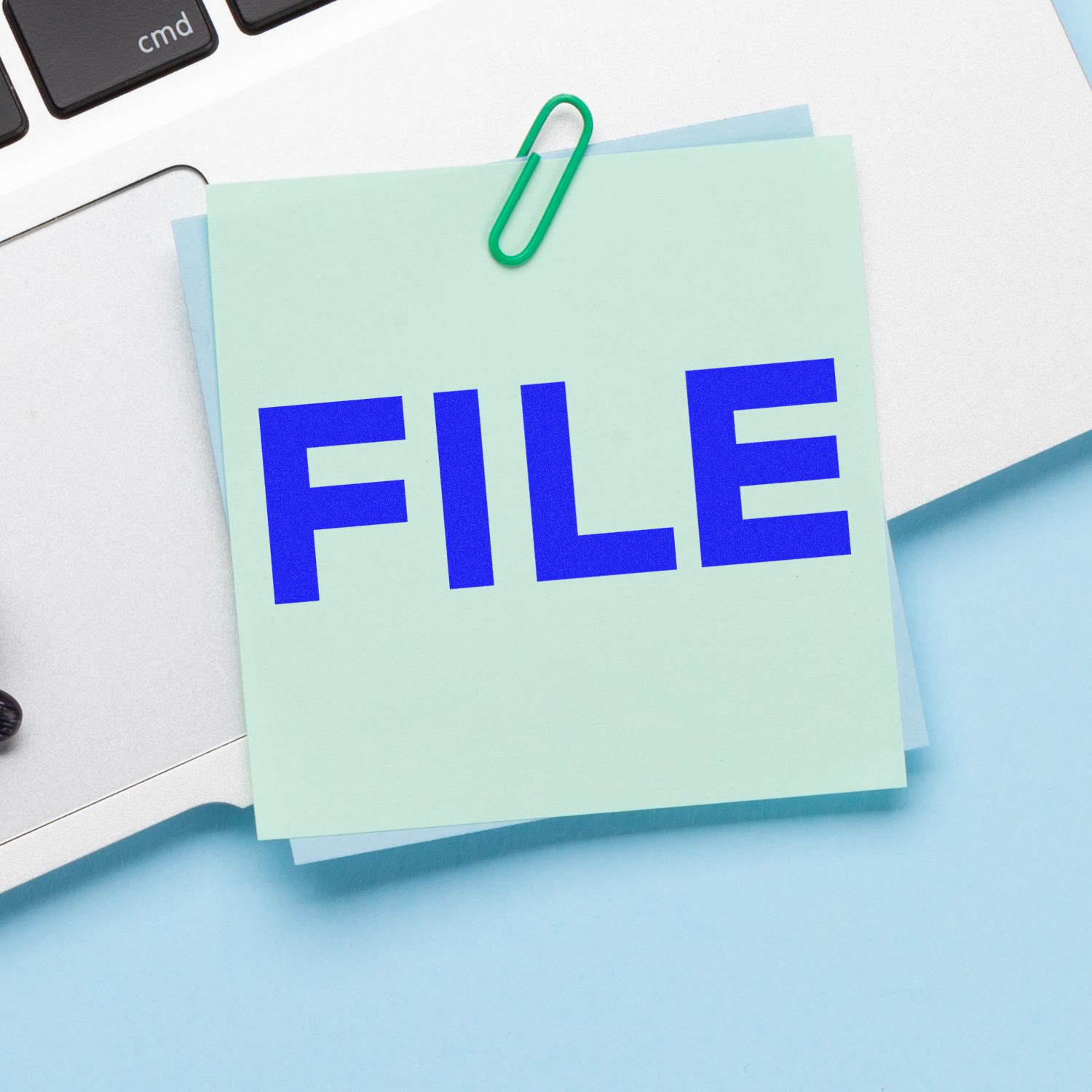Close-up of sticky note with the word FILE clipped to a desk, representing document organization and office file management.