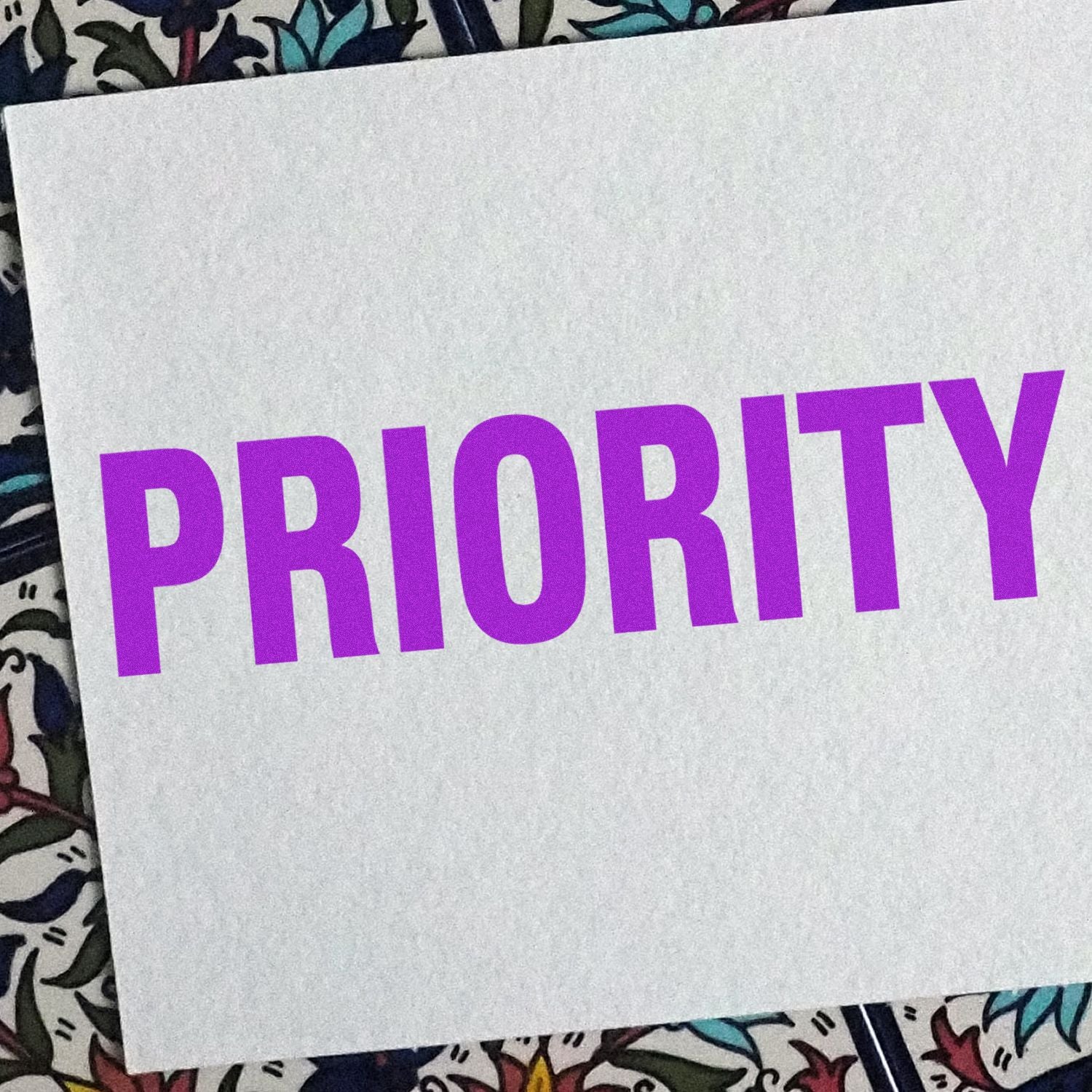 PRIORITY text in bold purple letters on a white card, used for branding, messaging, or priority announcement decor.