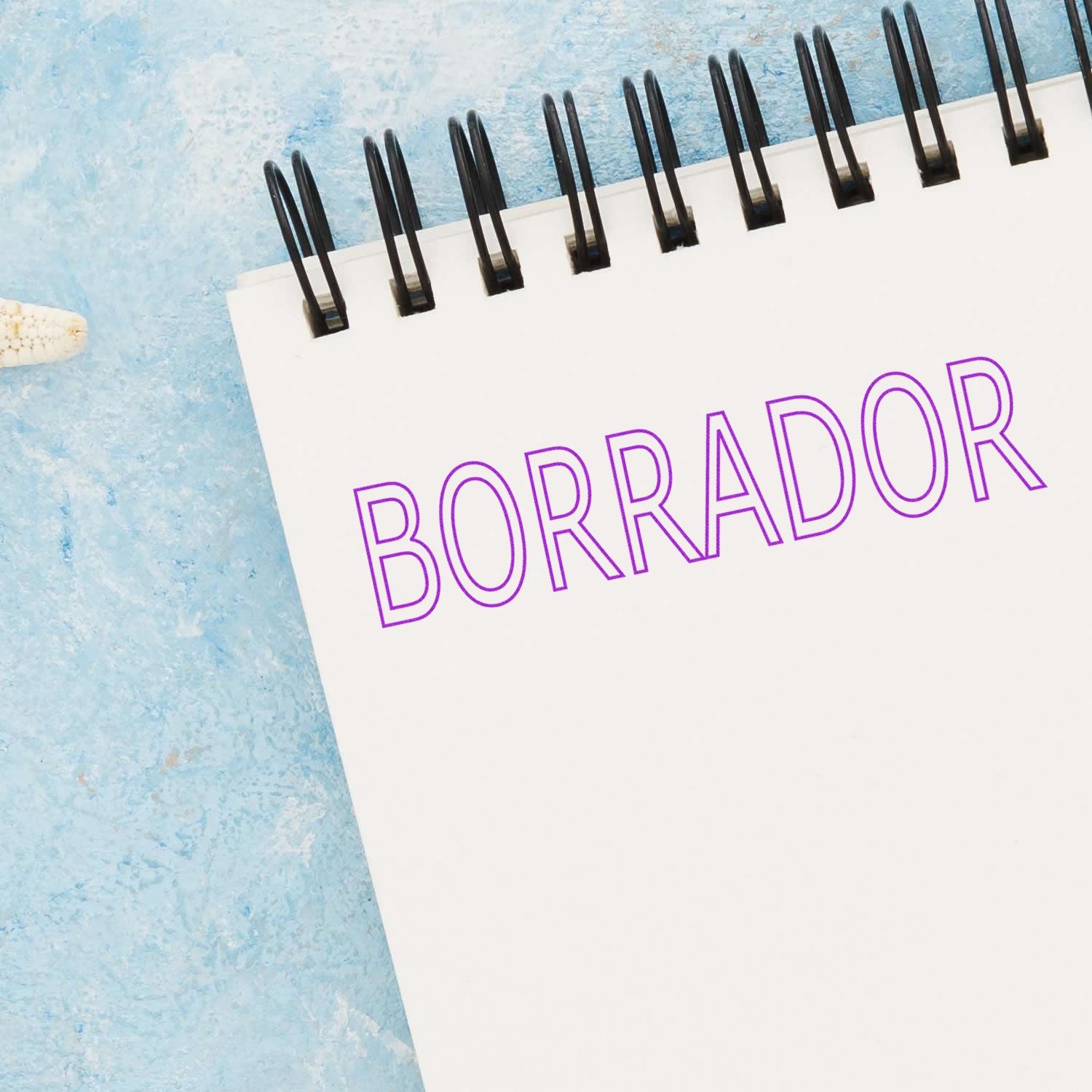 Spiral notebook with BORRADOR text, concept of a draft document on a blue textured background.
