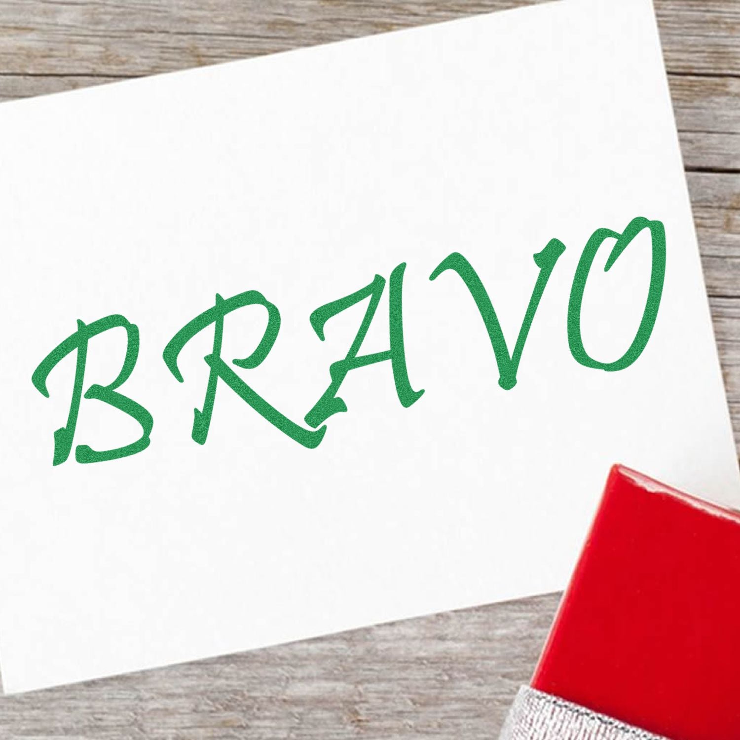 Handwritten green BRAVO card on a wooden table, expressing praise and celebration with a red accent.