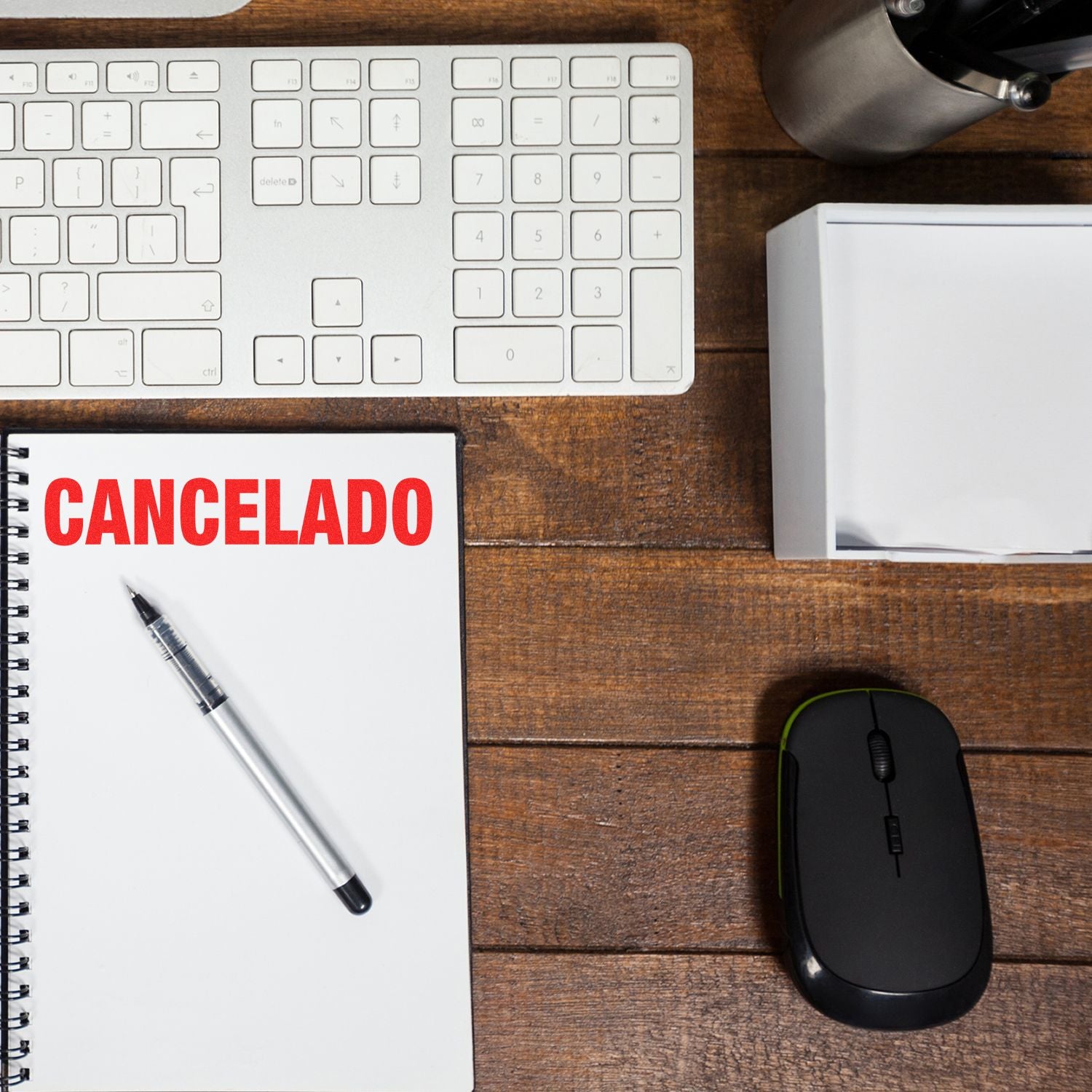 Office desk with keyboard, mouse, and notebook labeled CANCELADO beside a pen and document box.
