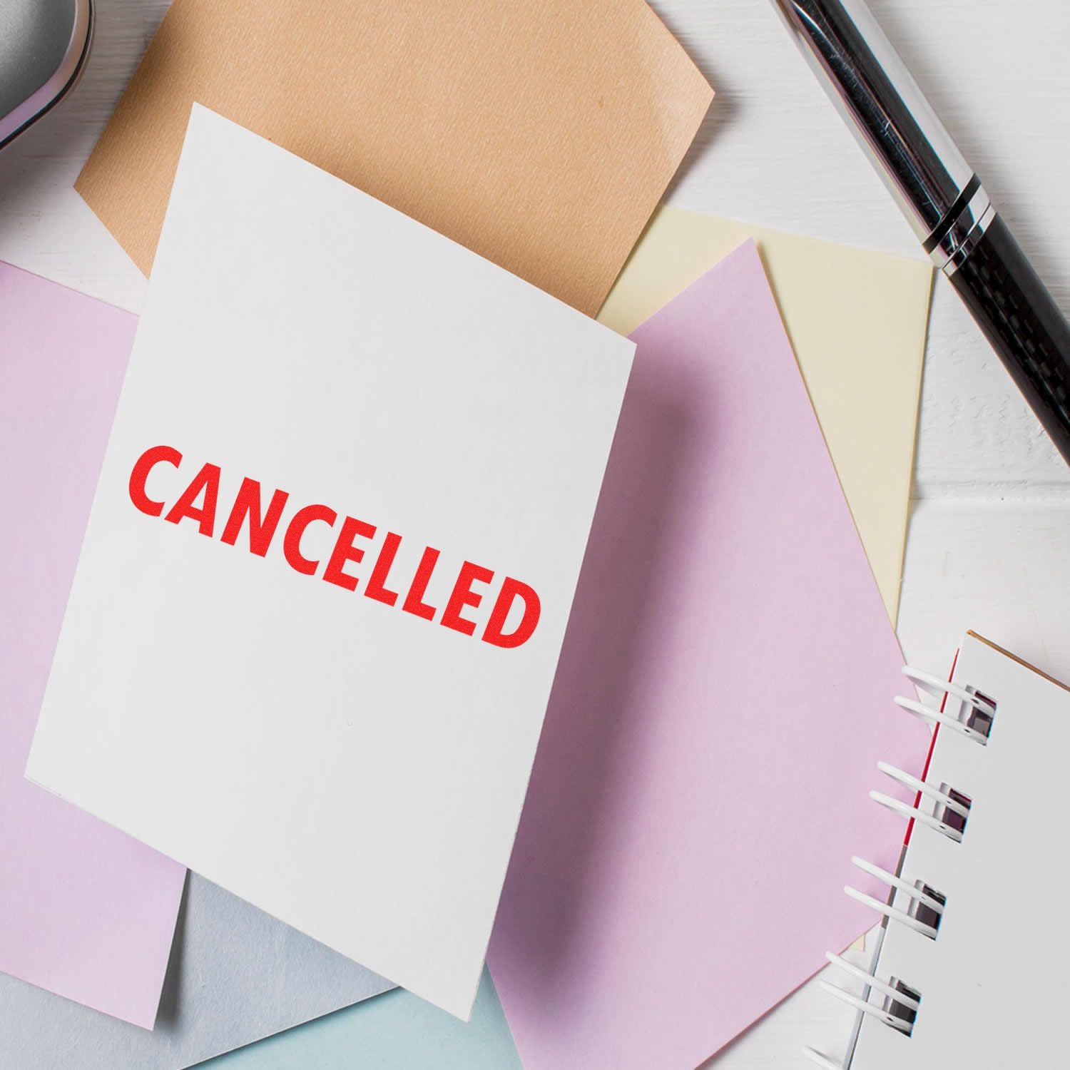 Cancelled paper documents and notebooks on desk, showing CANCELLED label for administrative cancellation or refund messaging