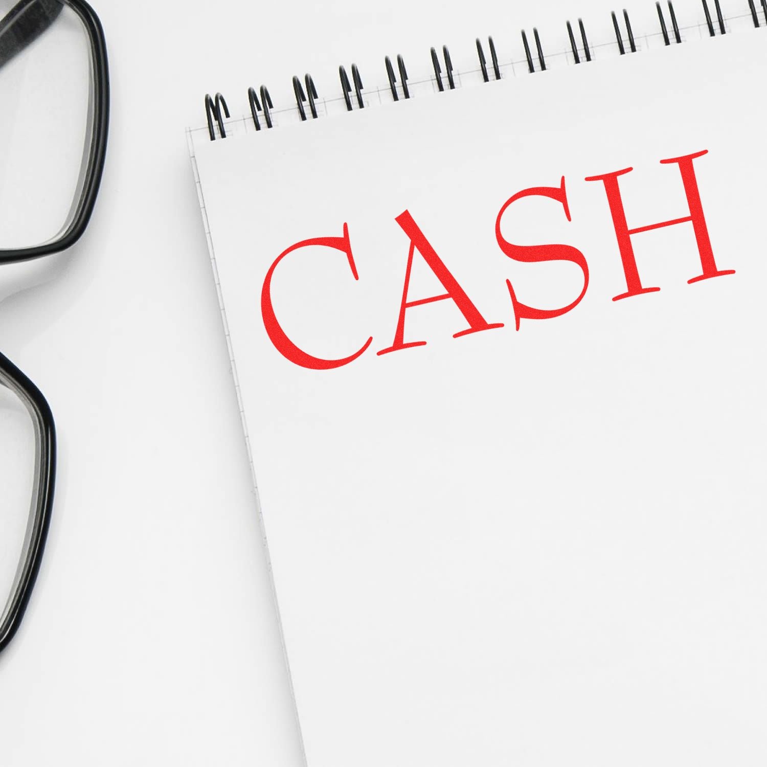 CASH text on a notebook with eyeglasses, symbolizing finance, budgeting, and money management.