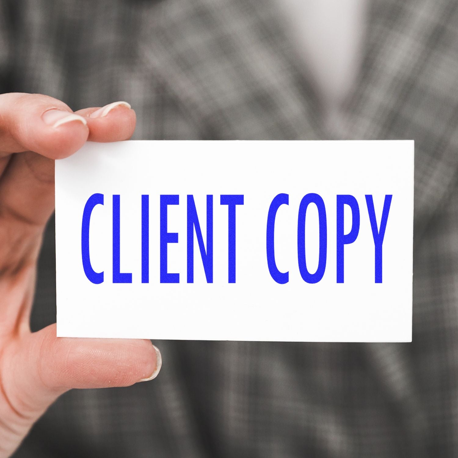 Hand holding a business card with blue CLIENT COPY text, symbolizing client document review and approval.