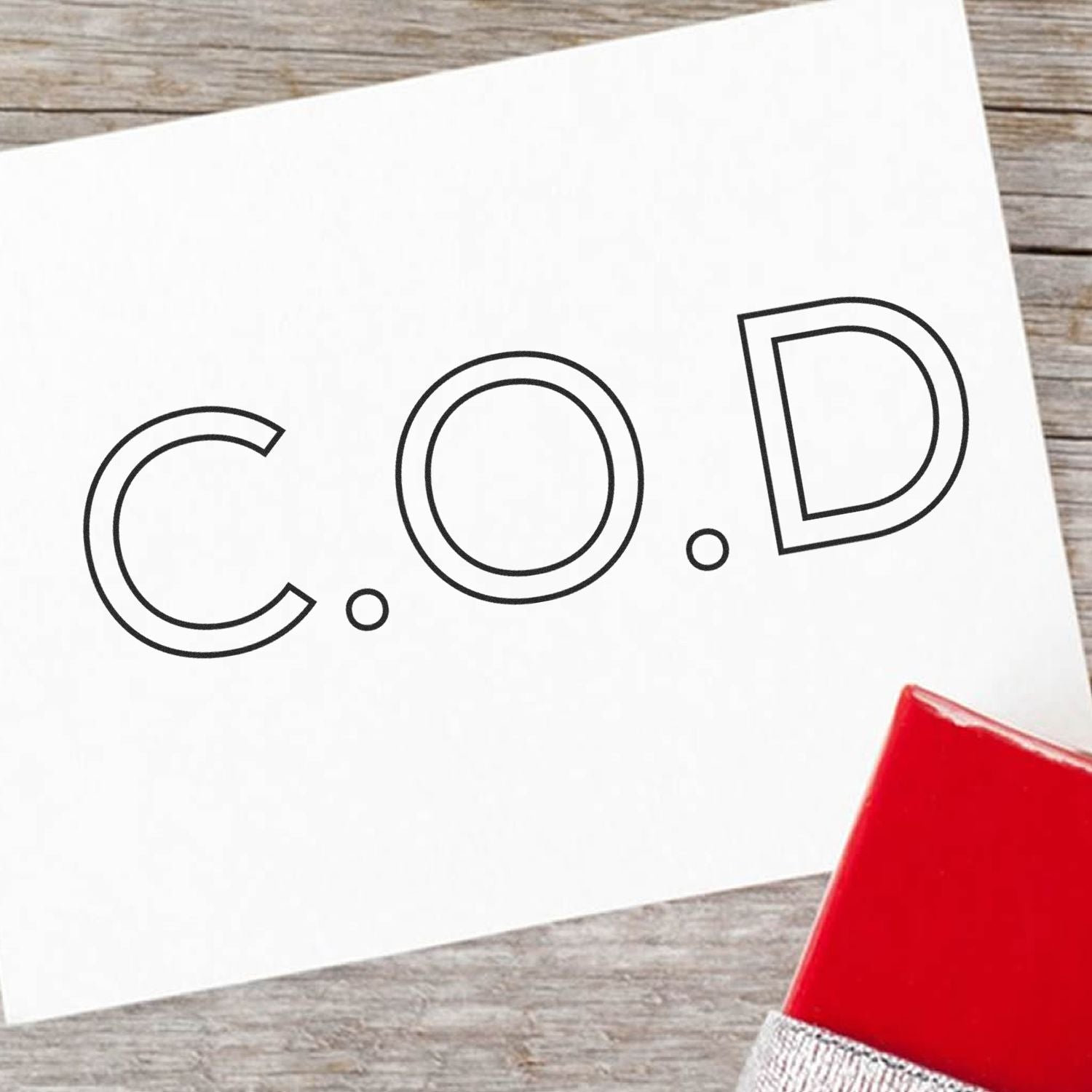 Close-up of COD letters printed on a white card for branding and typography design, placed on rustic wooden table.
