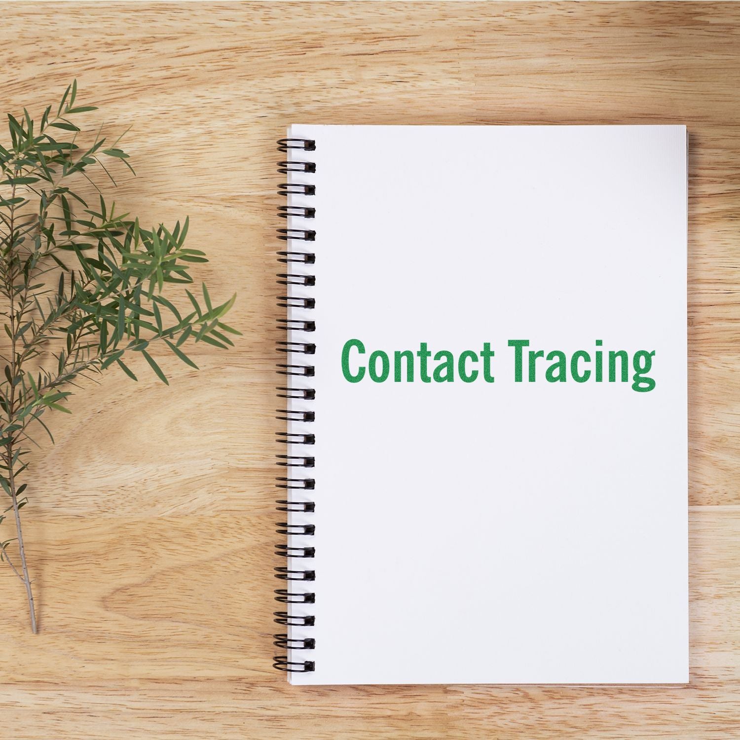 Contact tracing notebook on wooden desk with plant, promoting public health contact tracing services and registration.