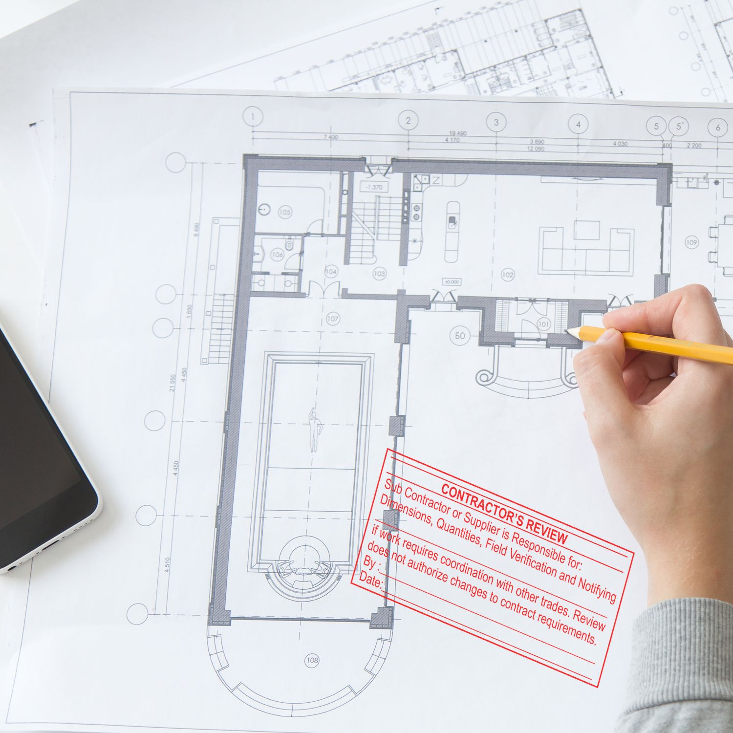 Hand marking architectural floor plan blueprint with pencil during contractor review and home design planning.