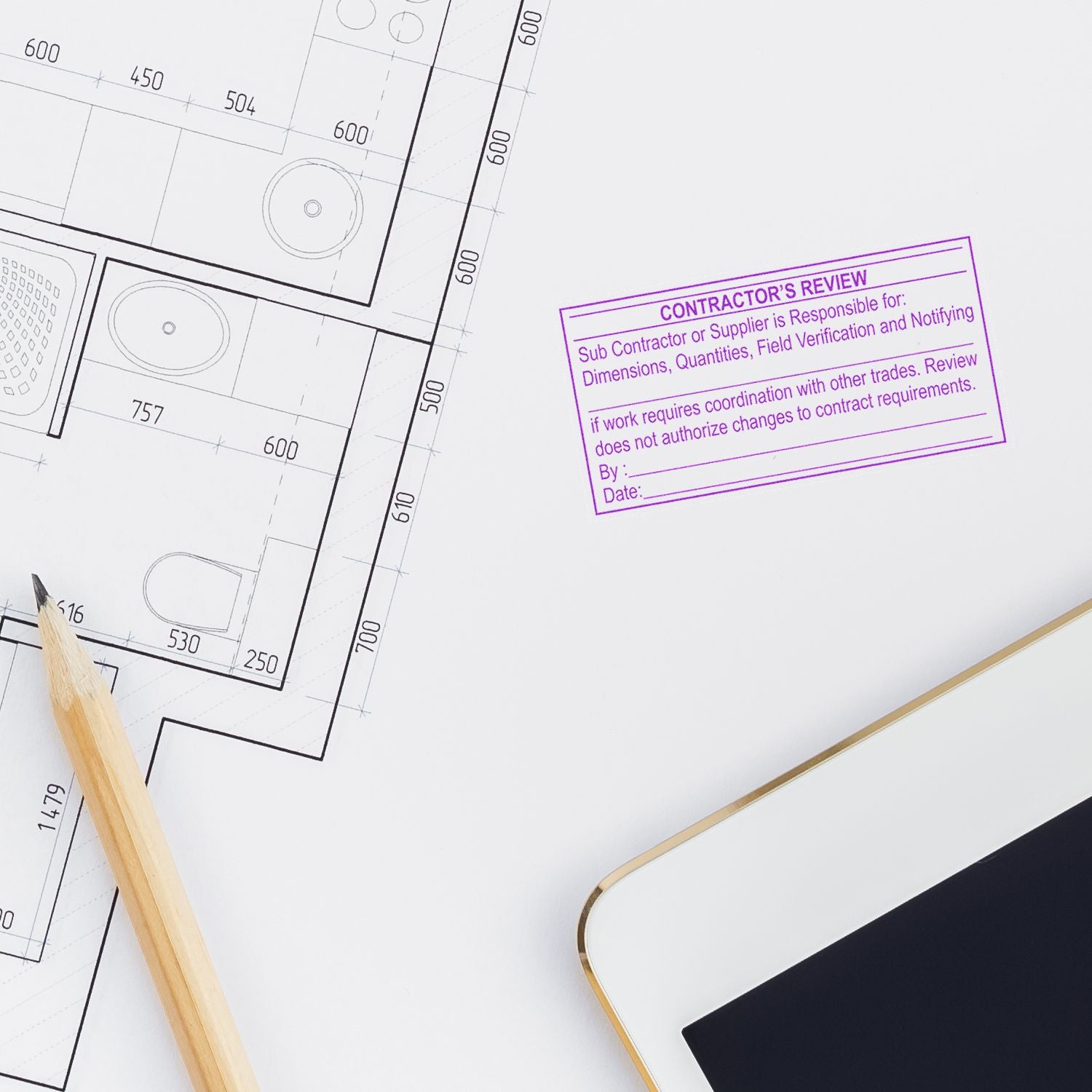 Architectural floor plan with pencil, tablet, and contractors review stamp on construction blueprint.