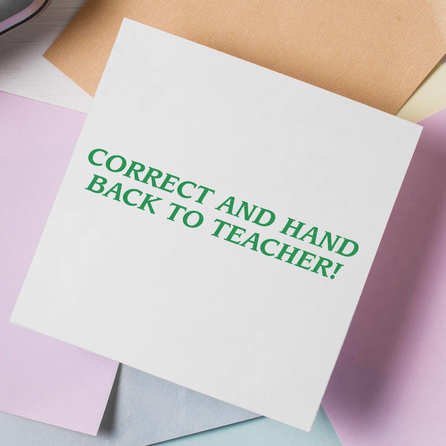 Green text on a white note card reading Correct and hand to teacher, a classroom reminder to submit assignments for grading.