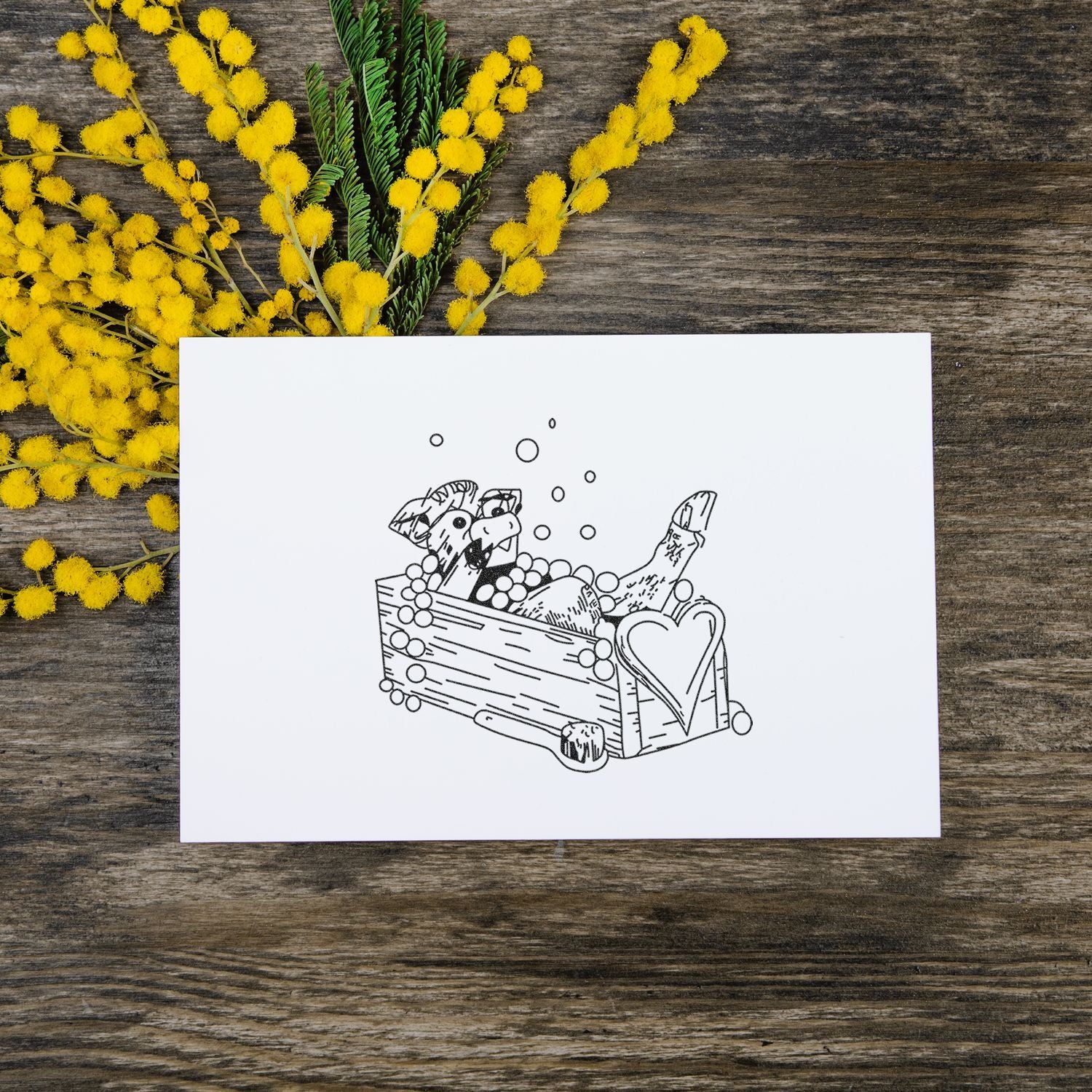 Easter greeting card with basket illustration on rustic wooden background, surrounded by yellow mimosa flowers.