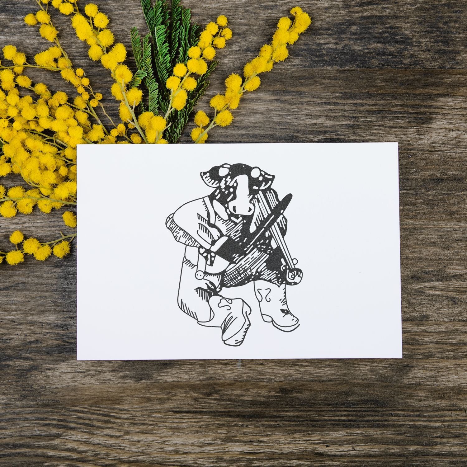 Handmade dog illustration card with yellow mimosa flowers on a rustic wooden background.