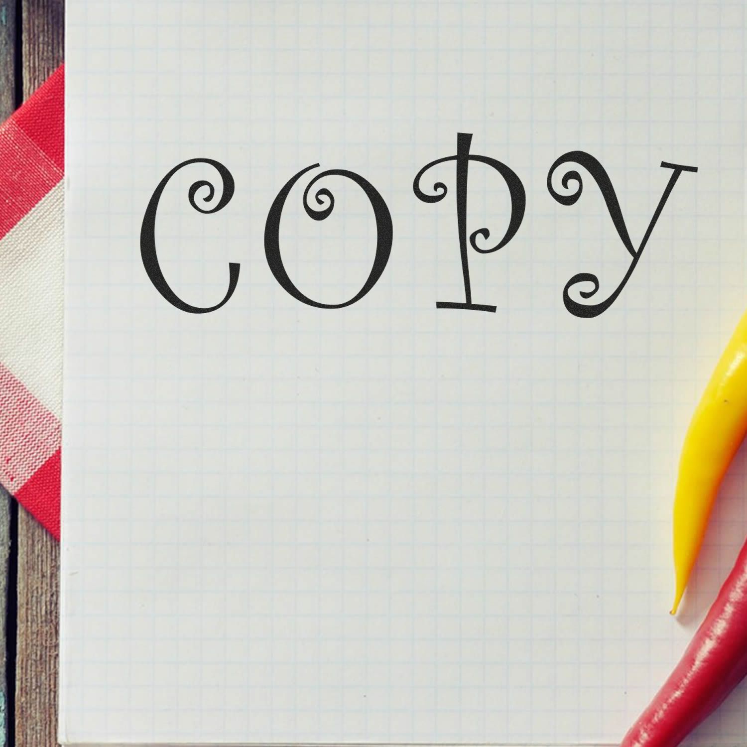 COPY word in stylized script on graph paper with pencils, representing copywriting and creative writing practice for marketing and school projects