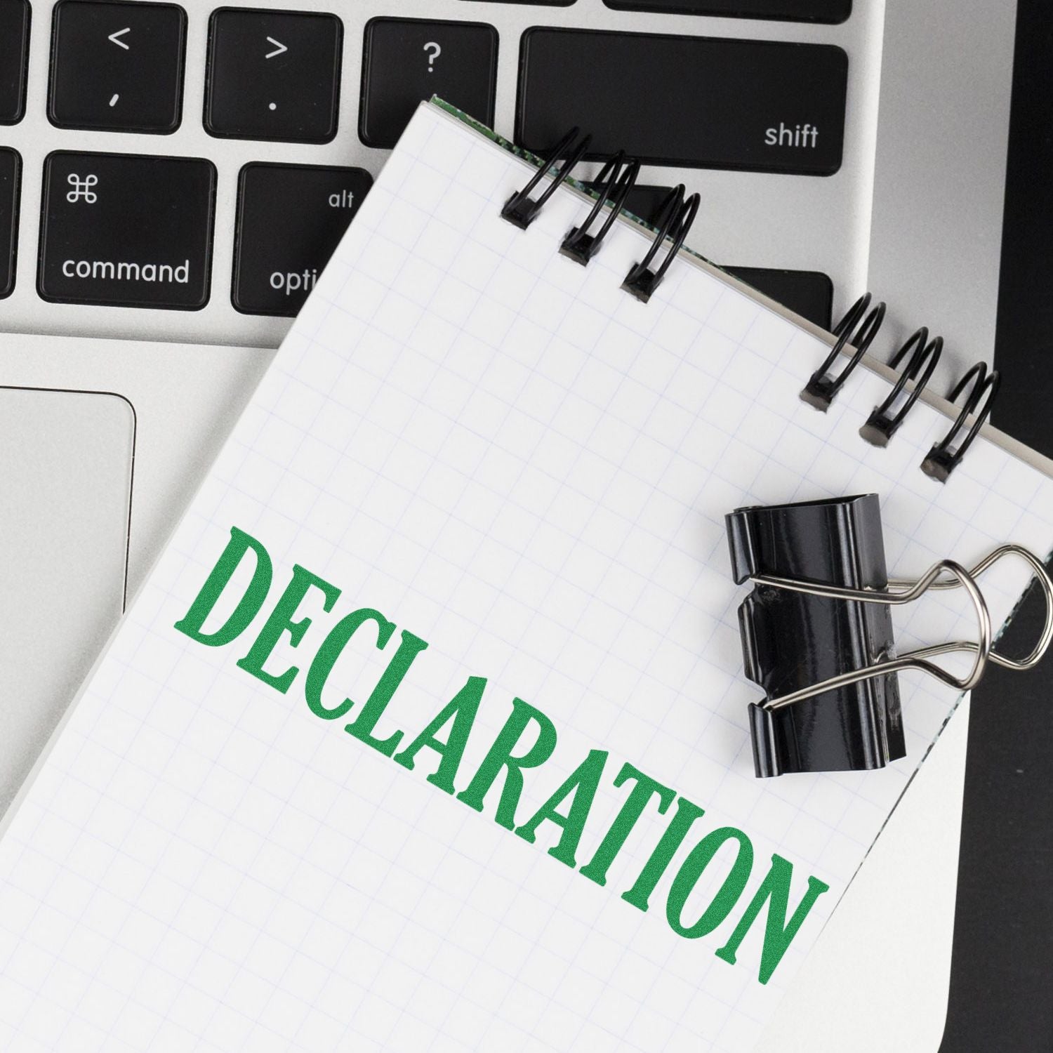 Declaration notebook with binder clips and keyboard keys, symbolizing legal paperwork and formal document preparation for business.