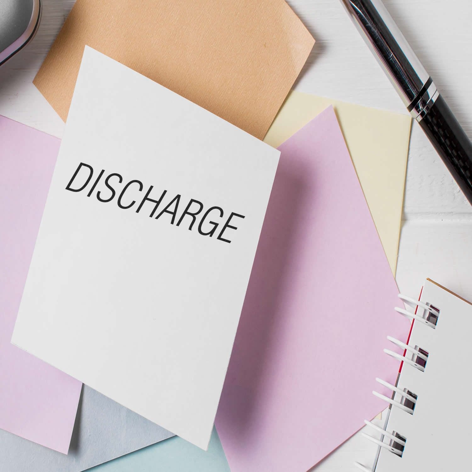 DISCHARGE paperwork concept with stationery, colored documents, and pen on desk for hospital discharge instructions