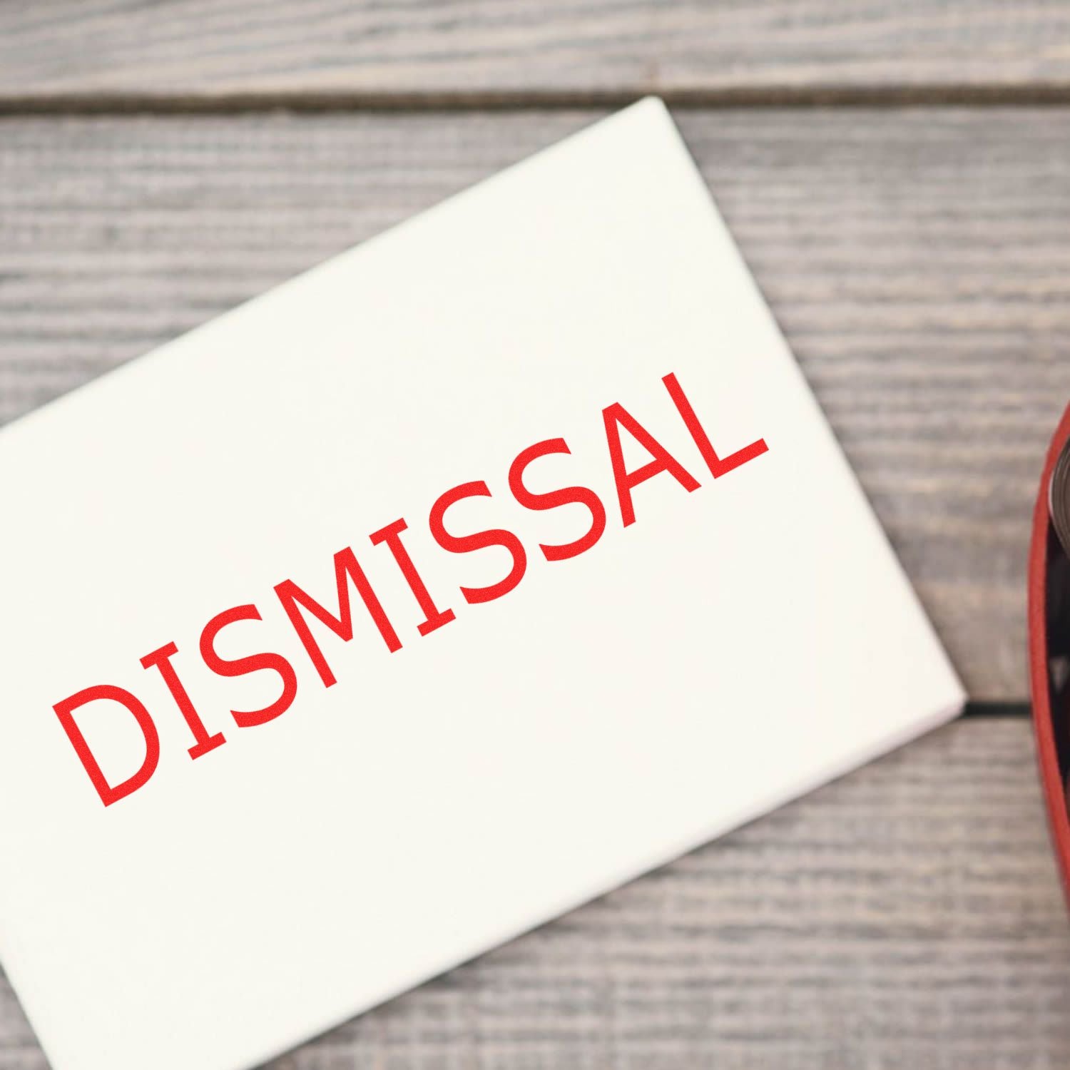 Close-up of a white document with red Dismisal text, indicating dismissal or termination paperwork.