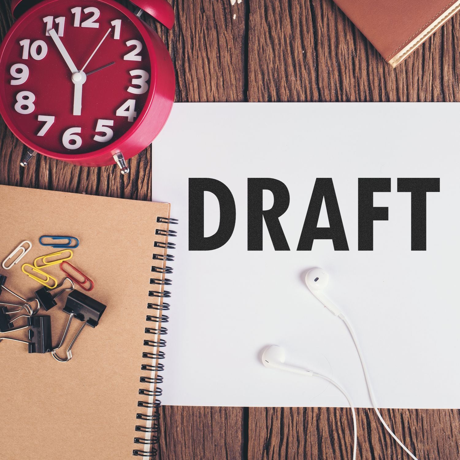 Draft concept image with alarm clock, office supplies, and headphones around a notebook page labeled DRAFT for planning ideas