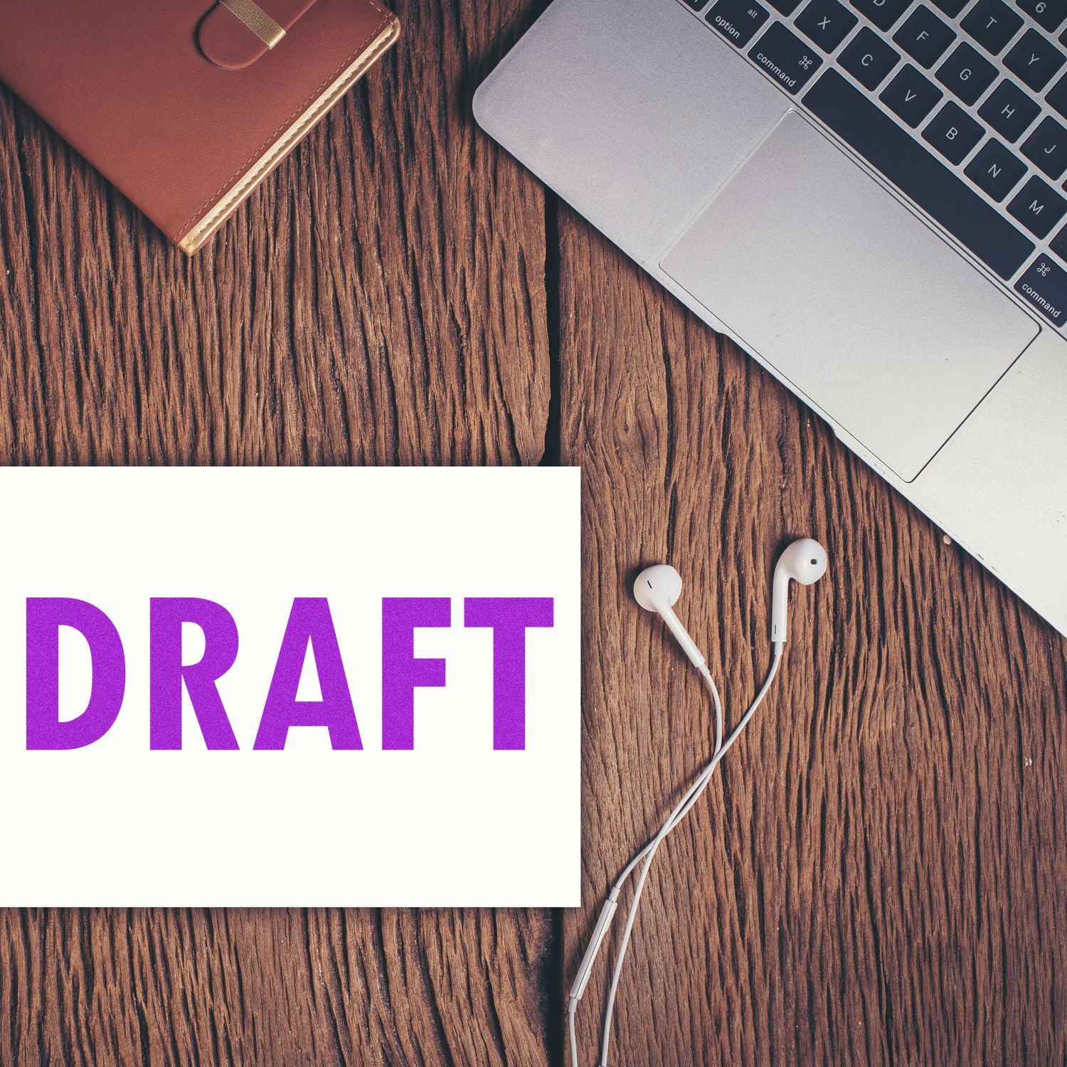 Draft concept on a wooden desk with laptop, earbuds, and DRAFT cardshowing content writing, editing, and review workflow.