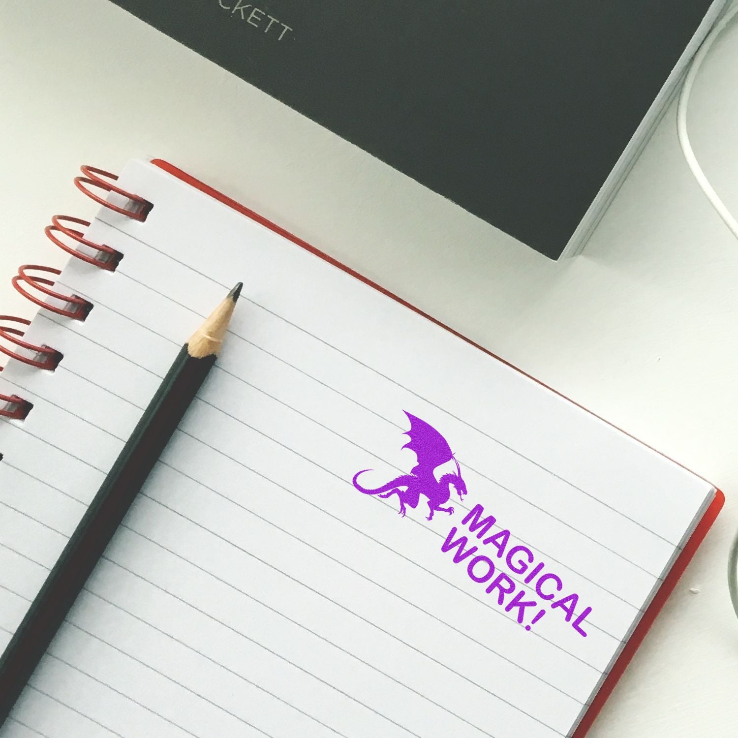 Magical notebook with pencil on desk, featuring a MAGICAL dragon emblem for spell journaling and creative writing