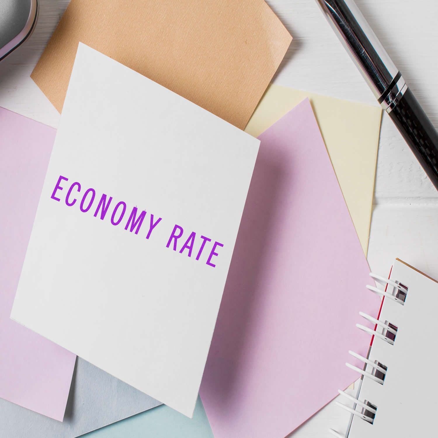 Economy rate concept on a notebook with pastel stationery and pen on a desk.