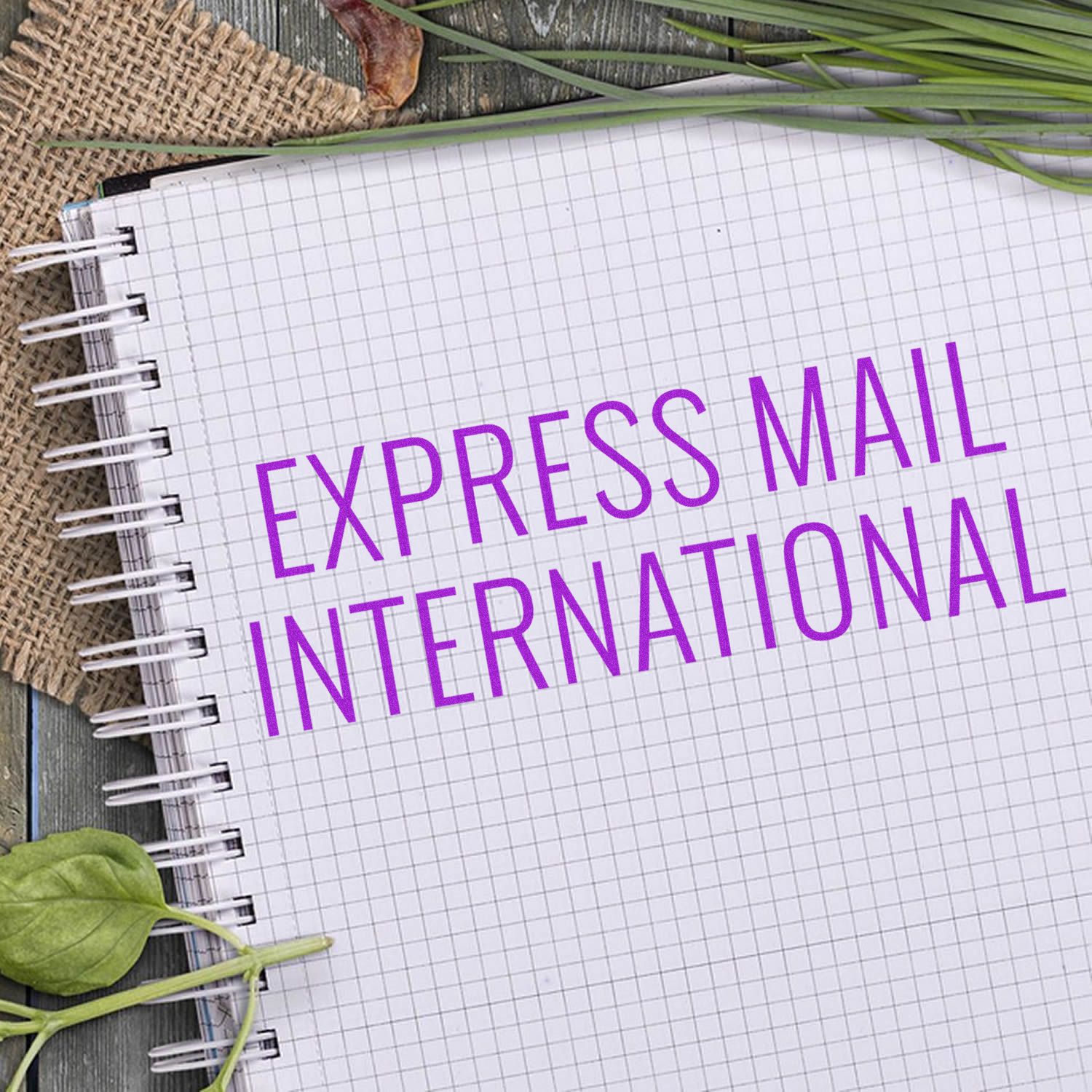 Express Mail International shipping label on grid notebook with green stems and leaves for international delivery services mailing.