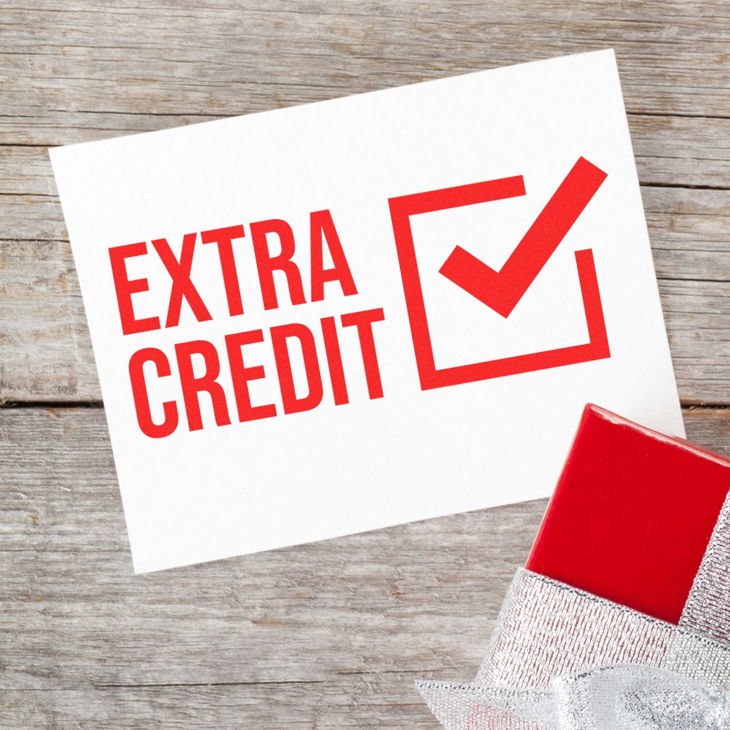 Extra credit sign with red checkmark and gift box on wooden background