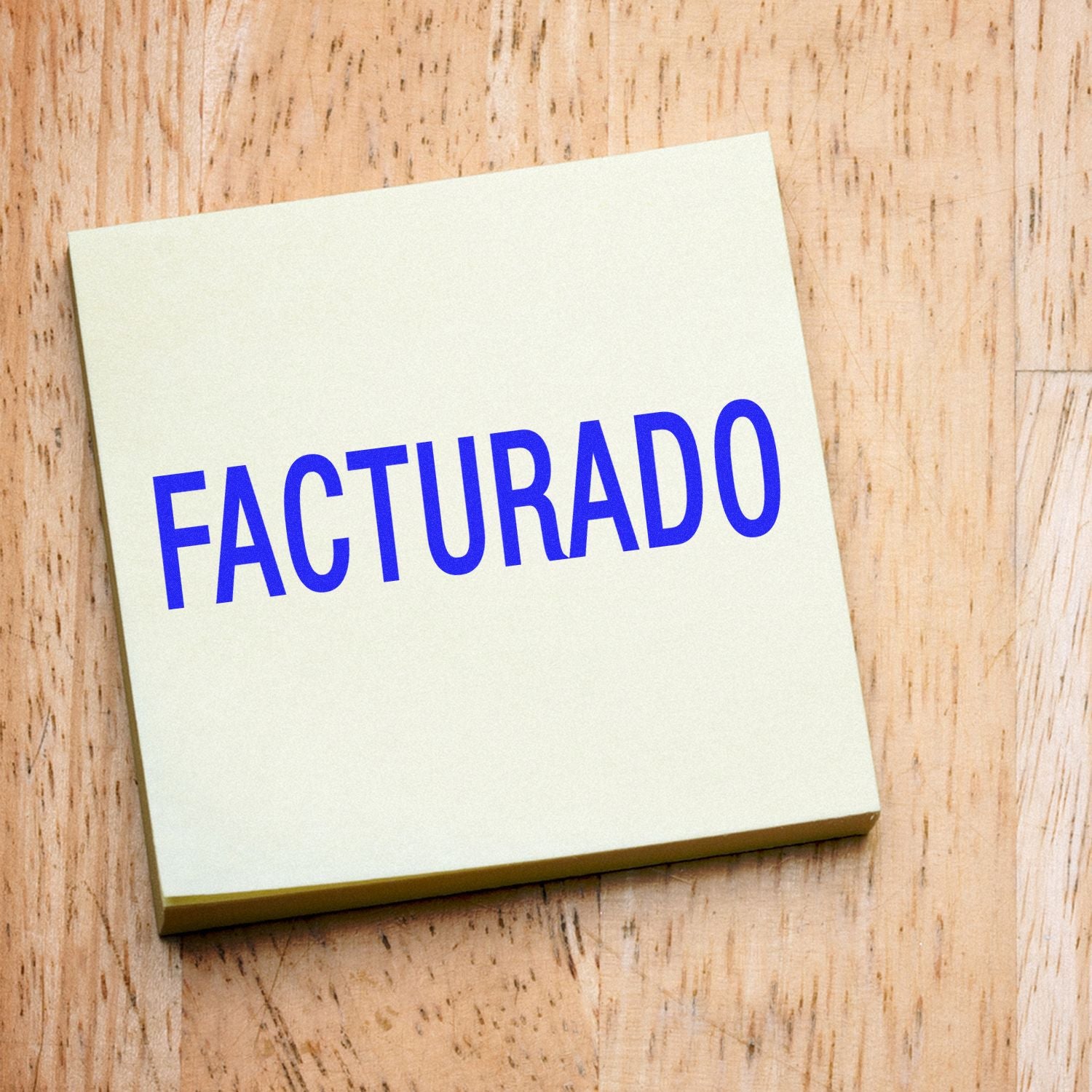 Sticky note with FACTURADO text on a wooden background, representing invoiced billing status.