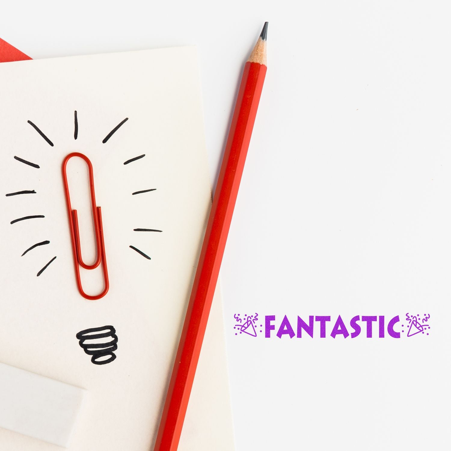 Red pencil beside a paperclip lightbulb sketch and Fantastic on white paper, creative stationery concept.