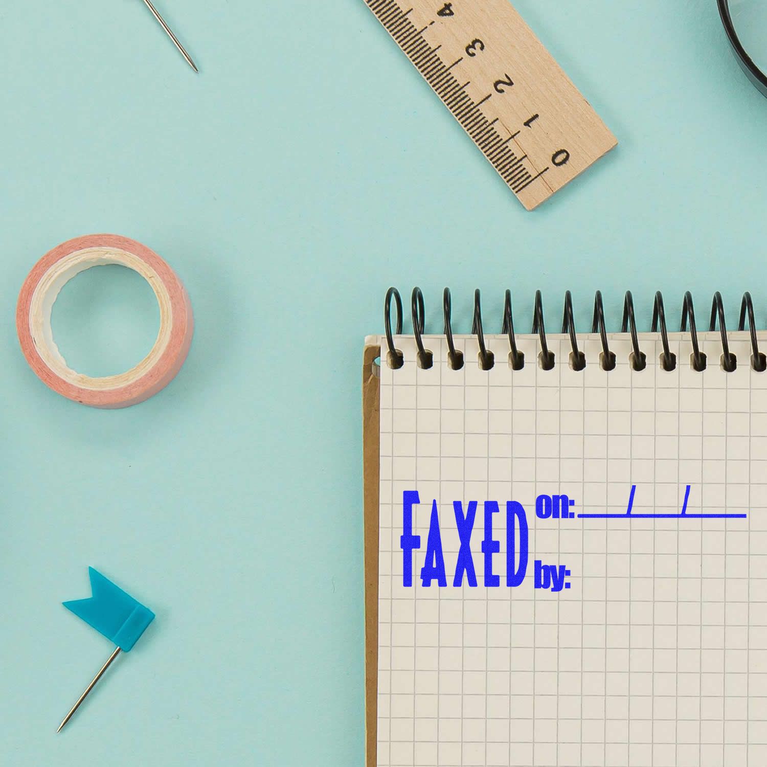 Ruler, pins, adhesive tape, and planner page on blue background for measurement planning and scheduling