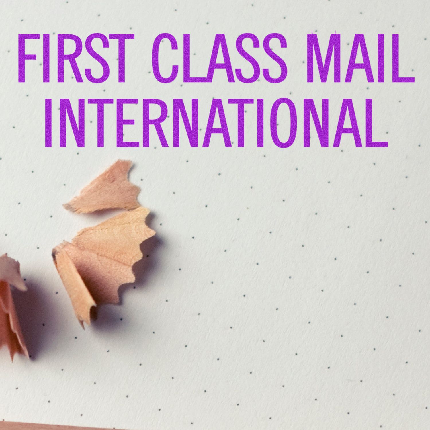 Purple First Class Mail International text on dotted paper with pencil shavings, office and mailing concept.