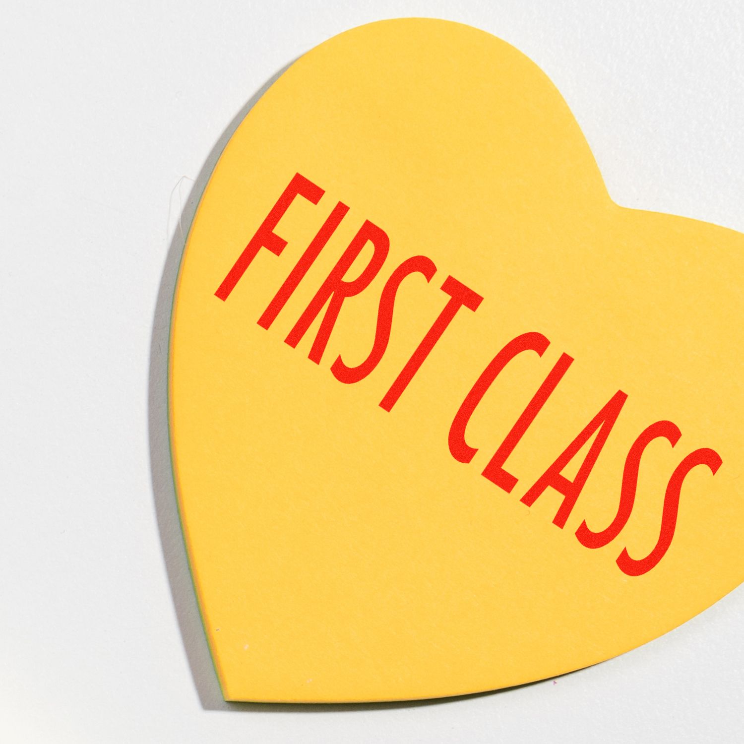 Yellow heart-shaped greeting card featuring red Happy Easter text on a white background.