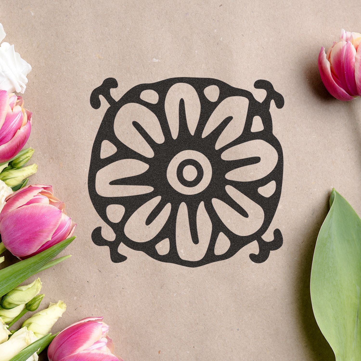 Black floral mandala design on kraft paper surrounded by pink and white tulips, elegant floral craft background.