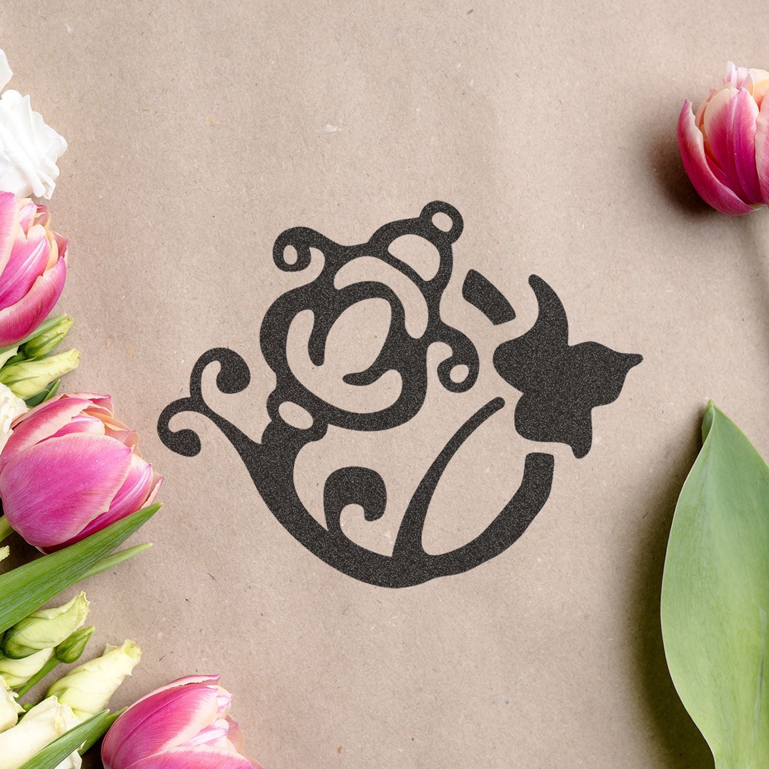 Decorative black floral logo on kraft paper surrounded by pink and white tulips, elegant spring flower packaging.