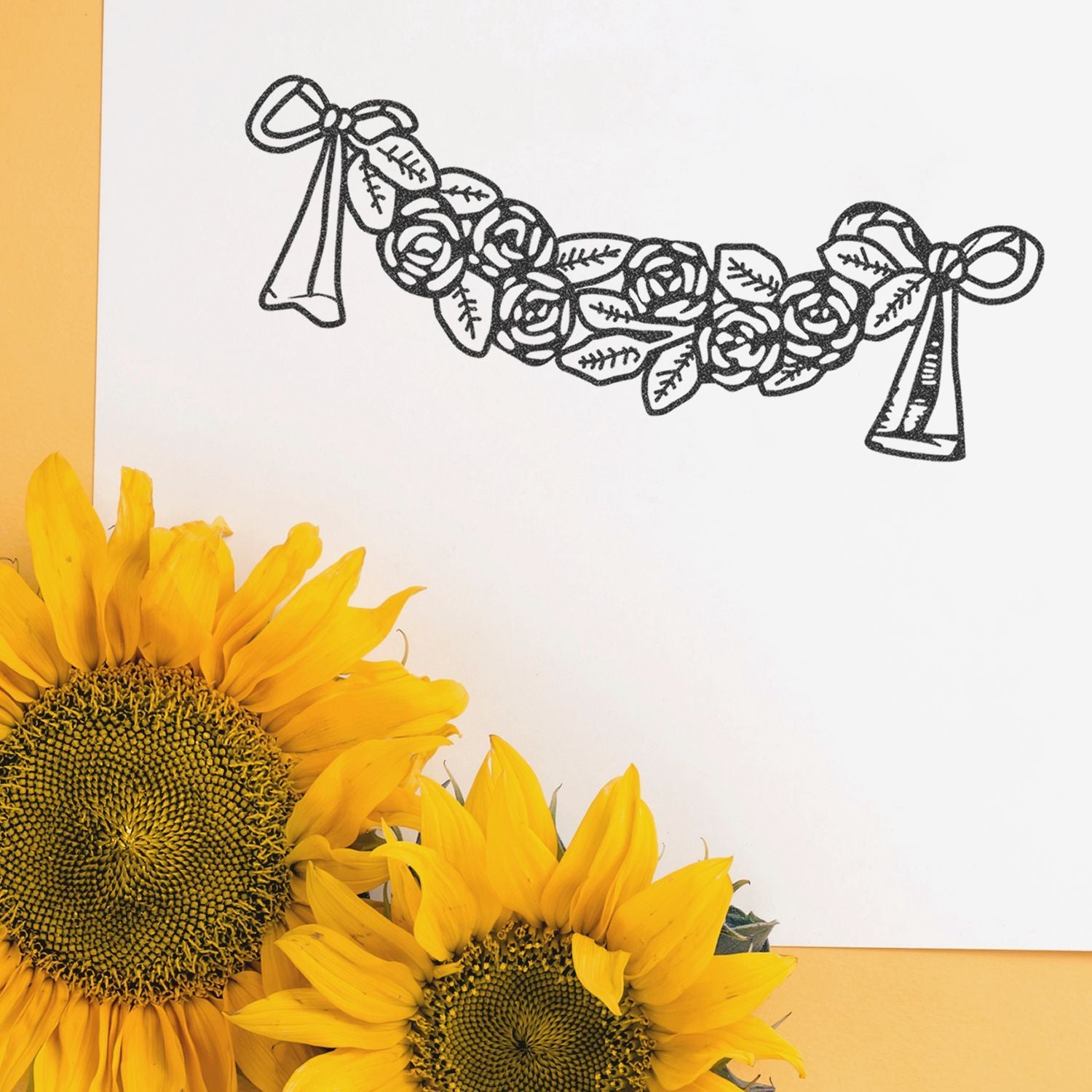 Sunflower-inspired floral garland sketch on white paper with bright yellow sunflowers in the foreground.