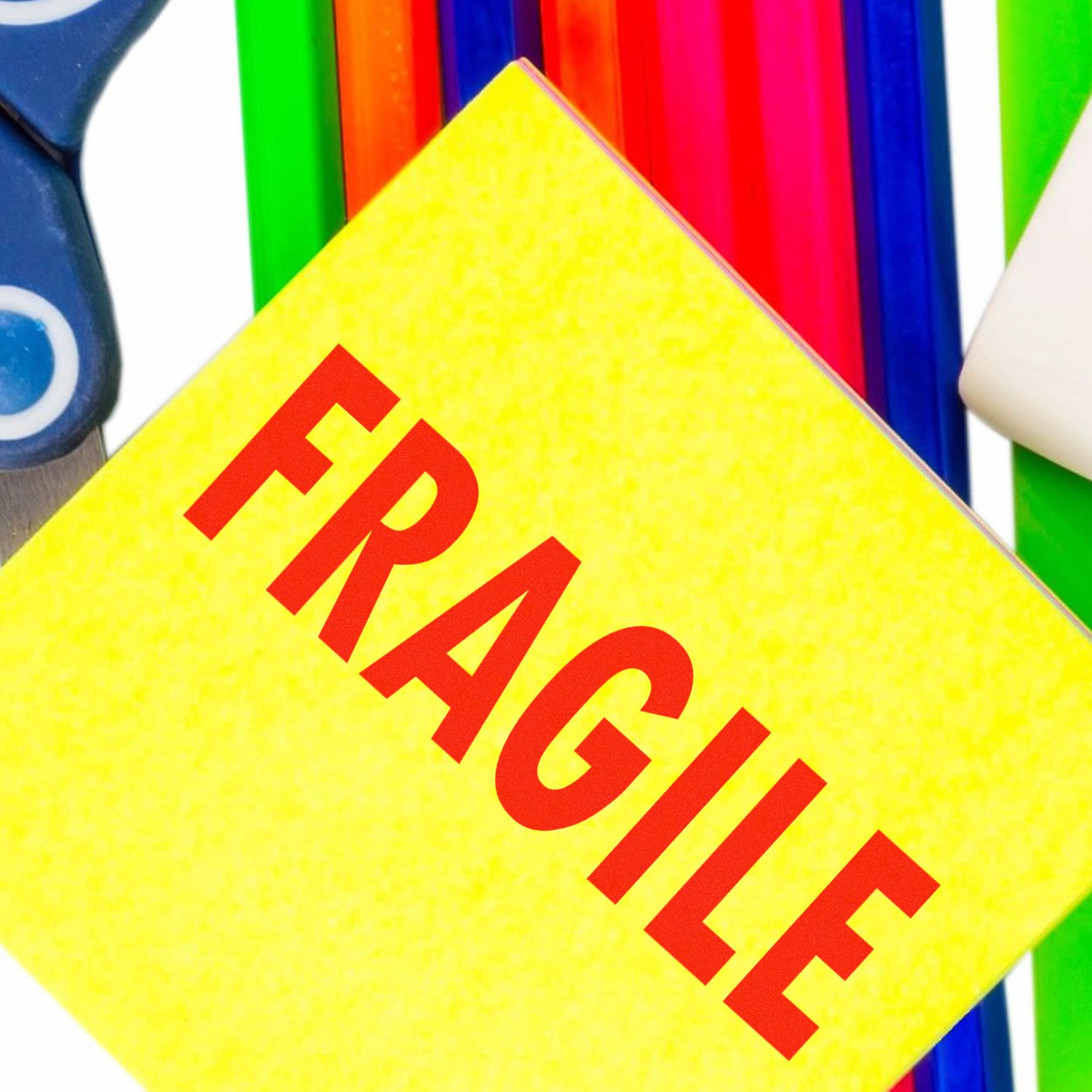 Yellow fragile warning label on colorful packaging materials and scissors background