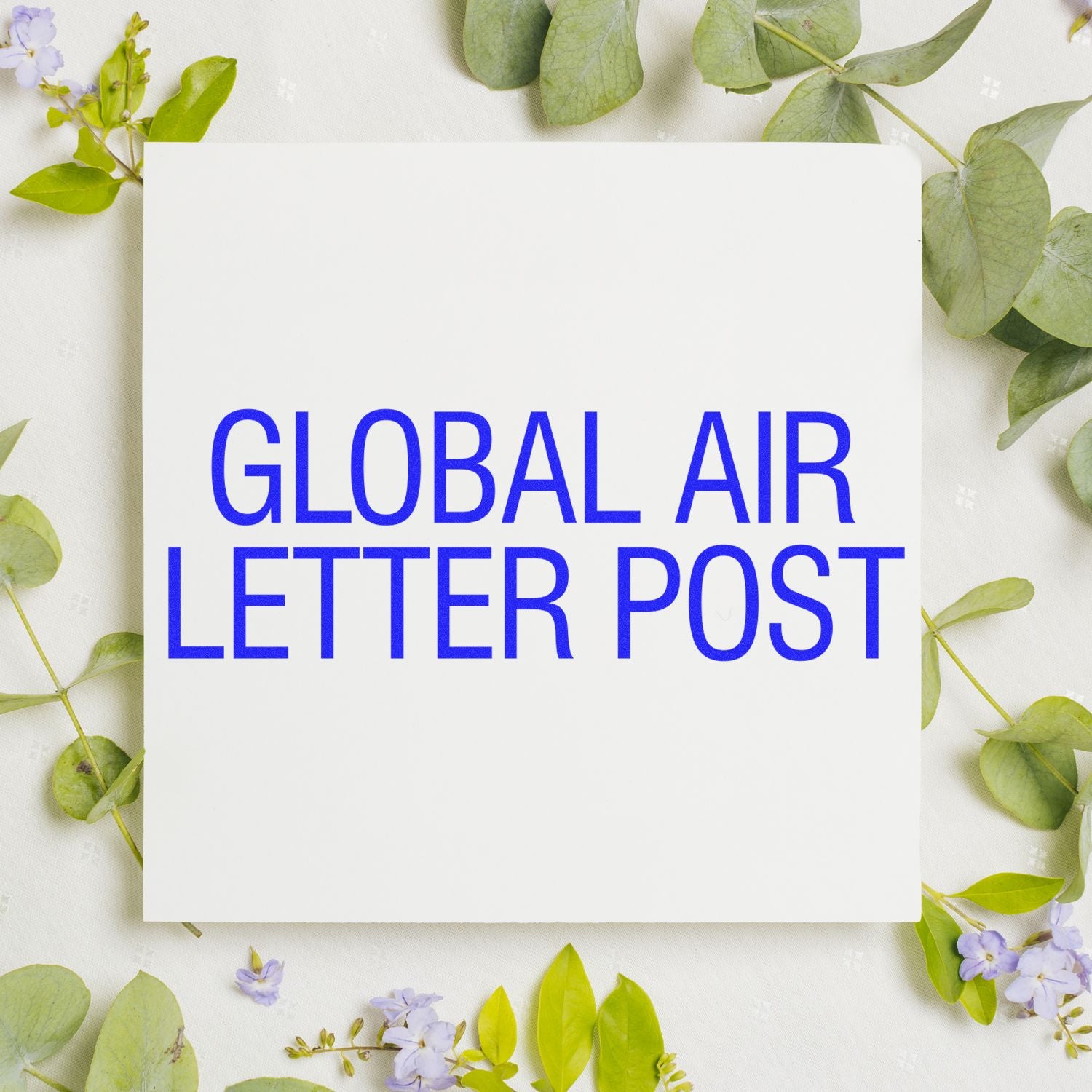 Global air letter post text on white card surrounded by green leaves and purple flowers on a light background