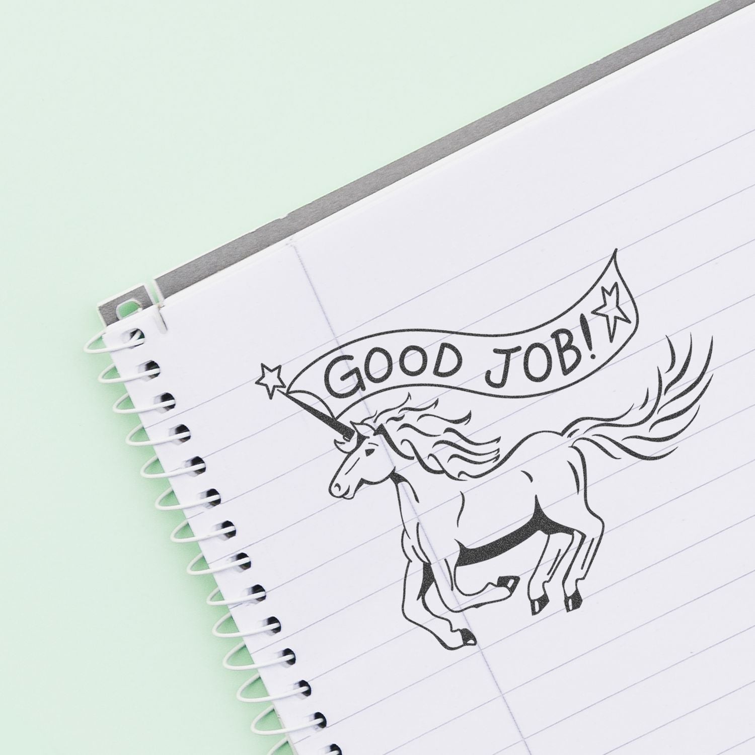 Notebook page with Good Job! unicorn illustration on lined paper, motivational sticker design.