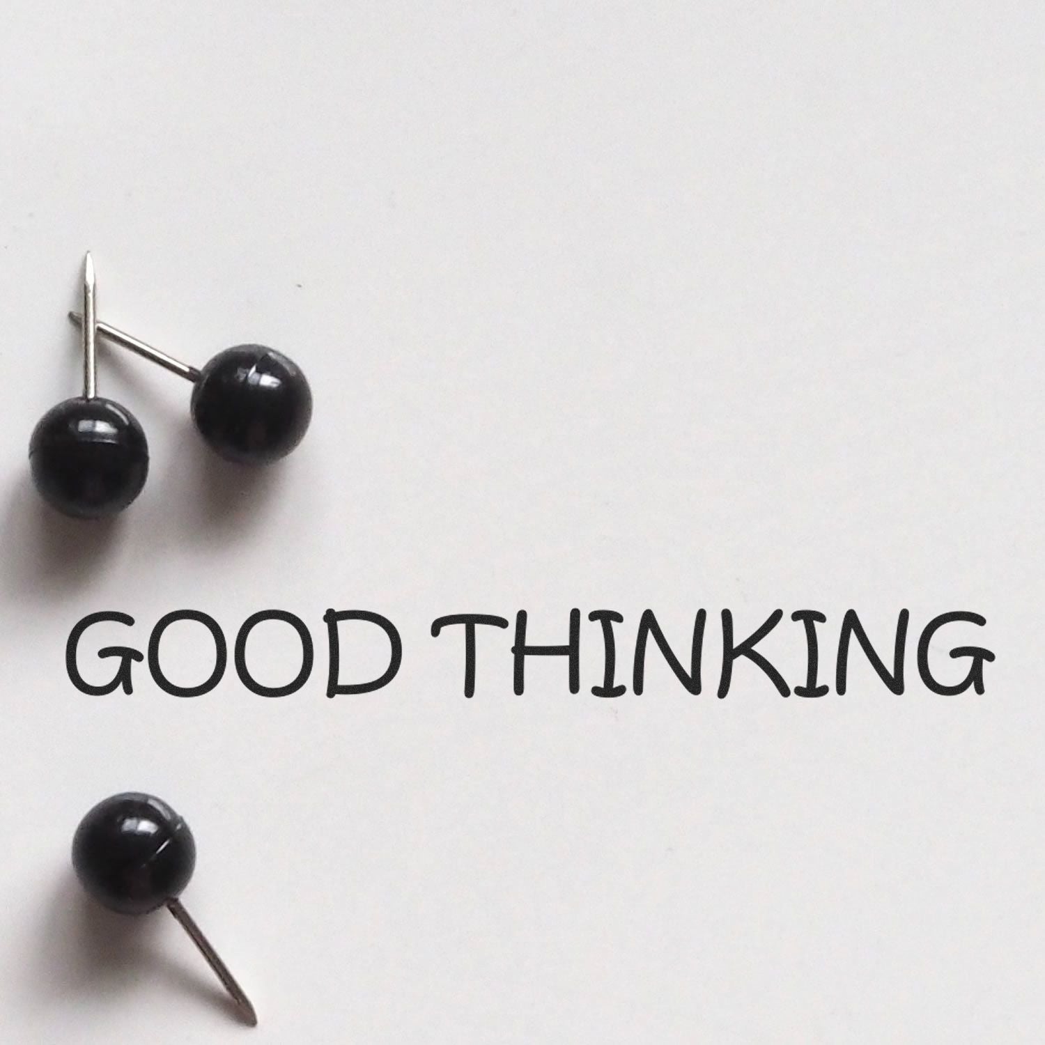 Black pushpins arranged to spell GOOD THINKING, symbolizing positive mindset and self-improvement on a white background.