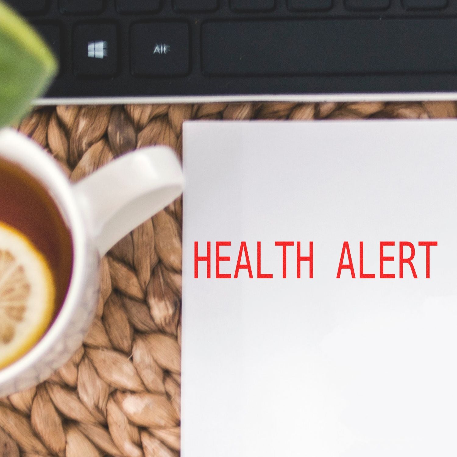 Health alert concept with laptop keyboard, coffee cup, and notebook on a desk workspace.